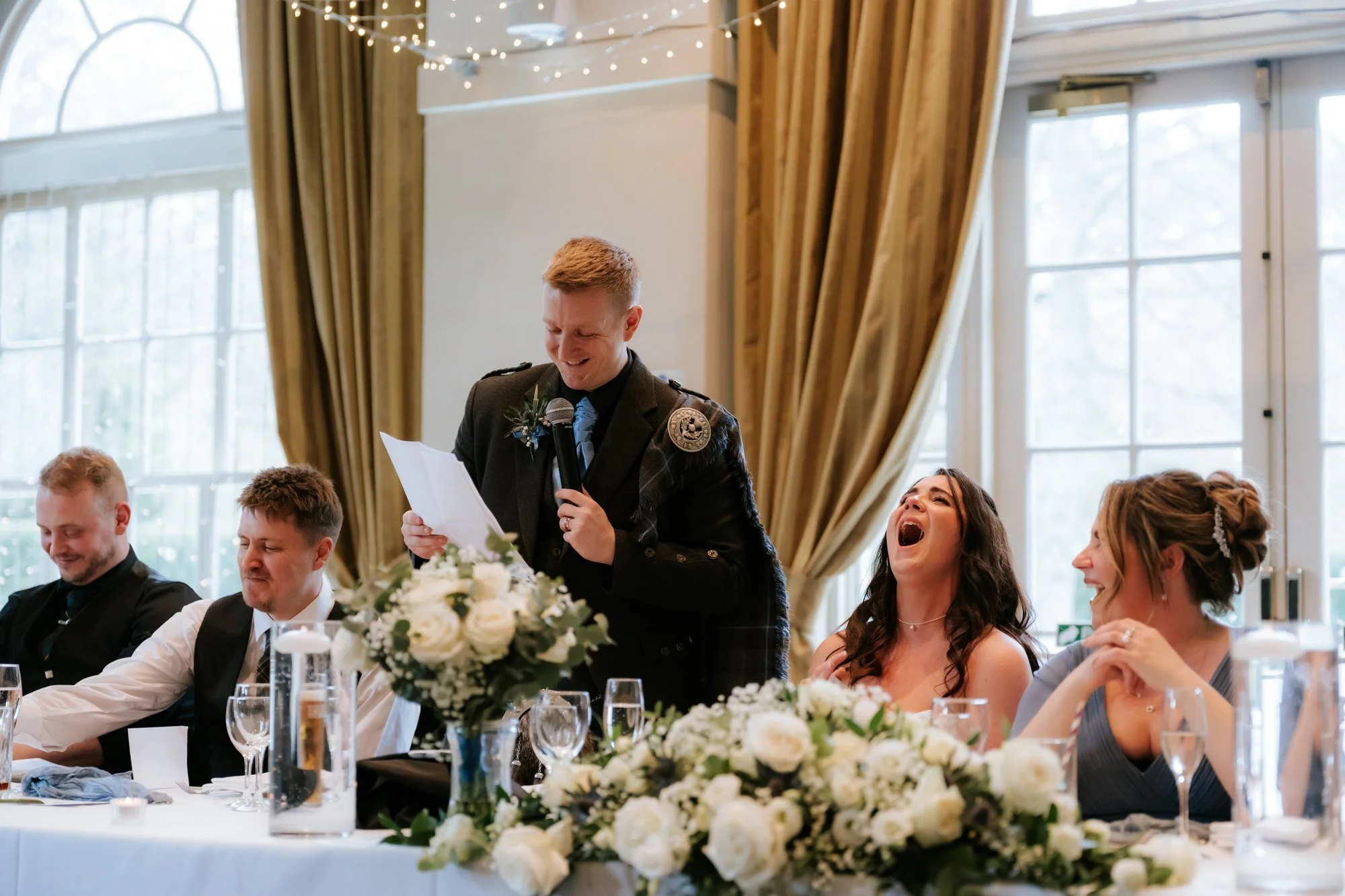 Calum giving his speech as Steph laughs beside him.
