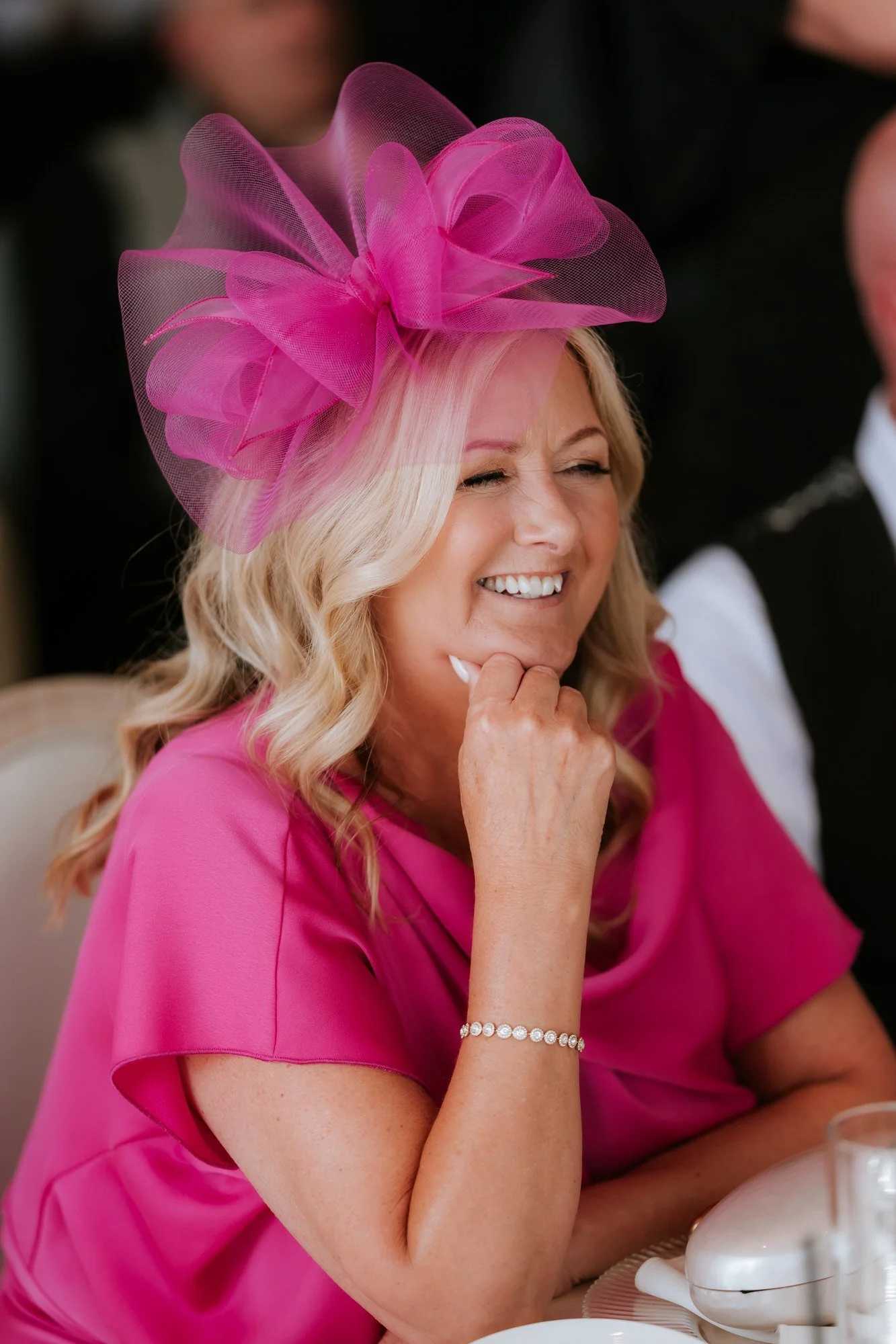 A guest in a pink hat enjoying the wedding reception.
