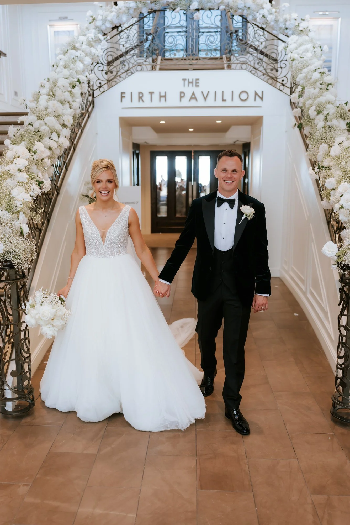 Nicole and Lawrence beside the flower-lined Firth Pavilion staircase.