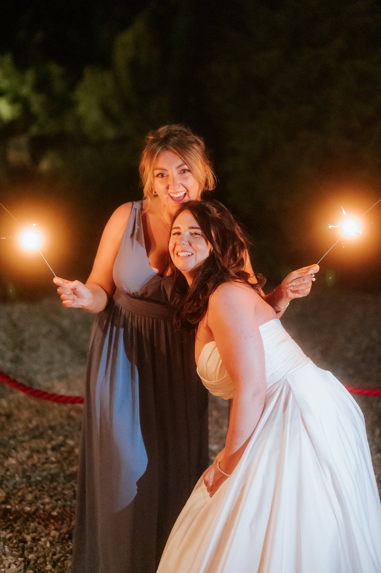 Steph celebrating with her bridesmaids and sparklers outside Balbirnie House.