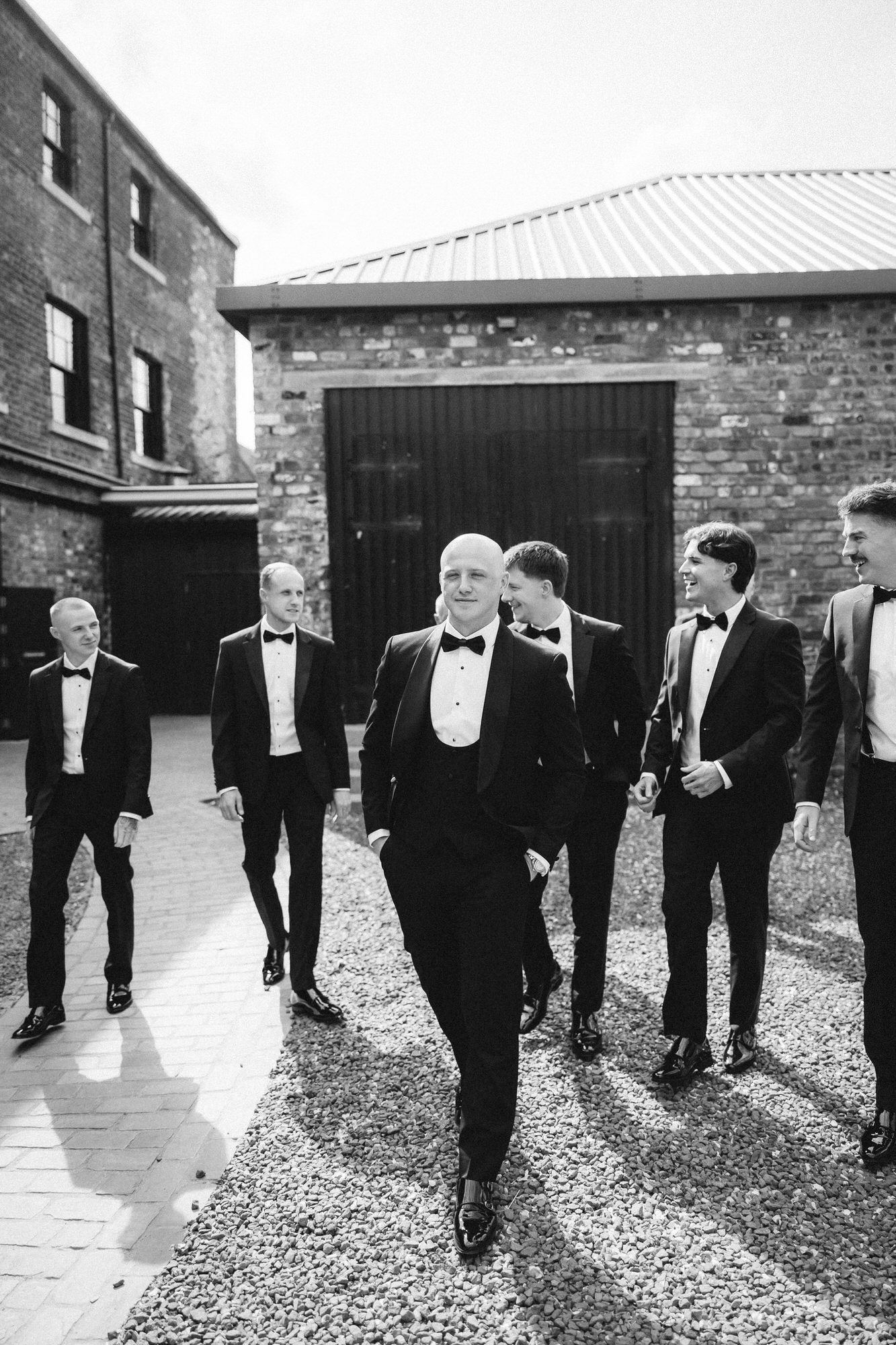 Craig and his friends in black tuxedos in the courtyard.
