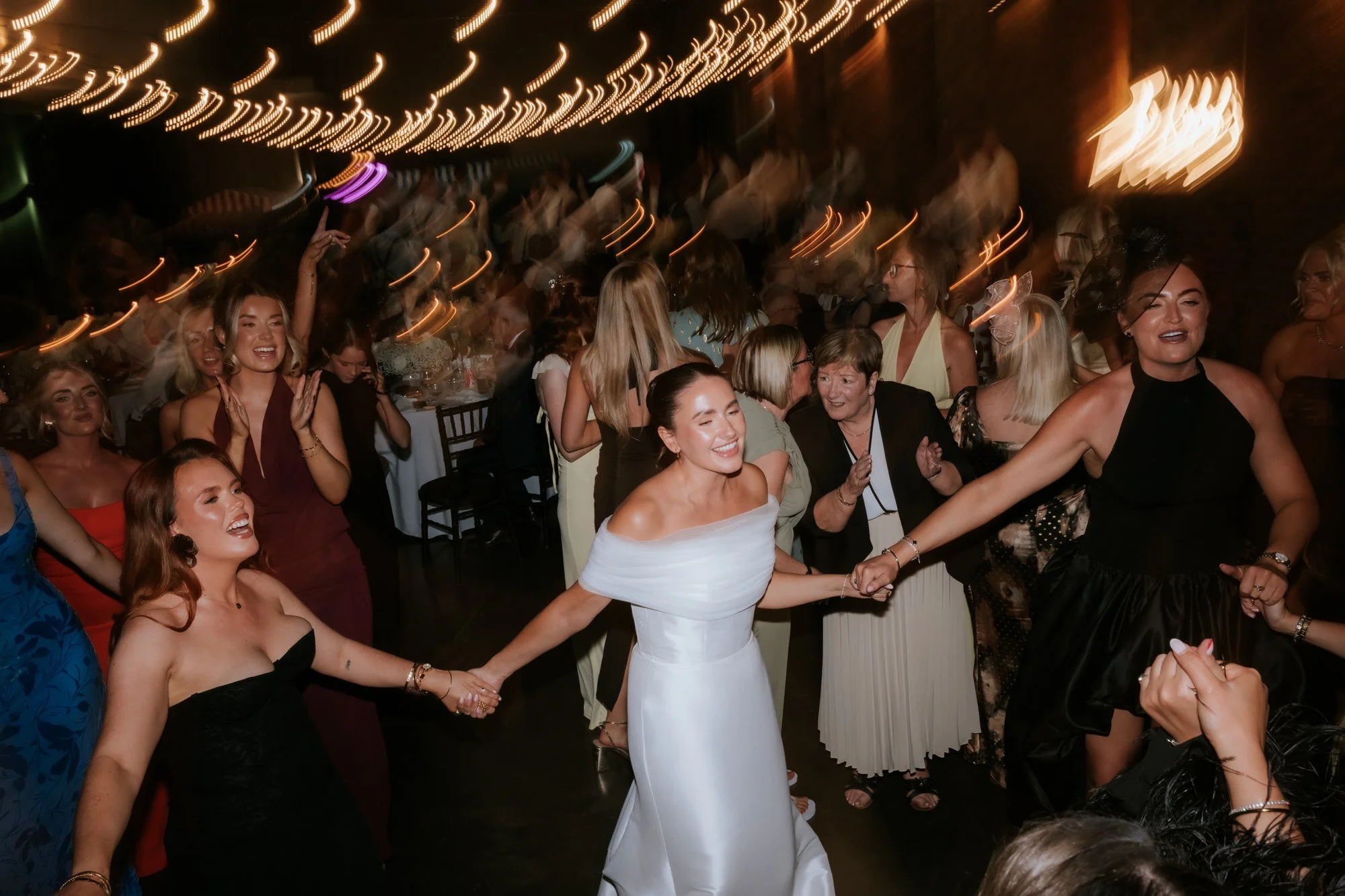 Caitlin dancing with friends beneath the warm string lights.