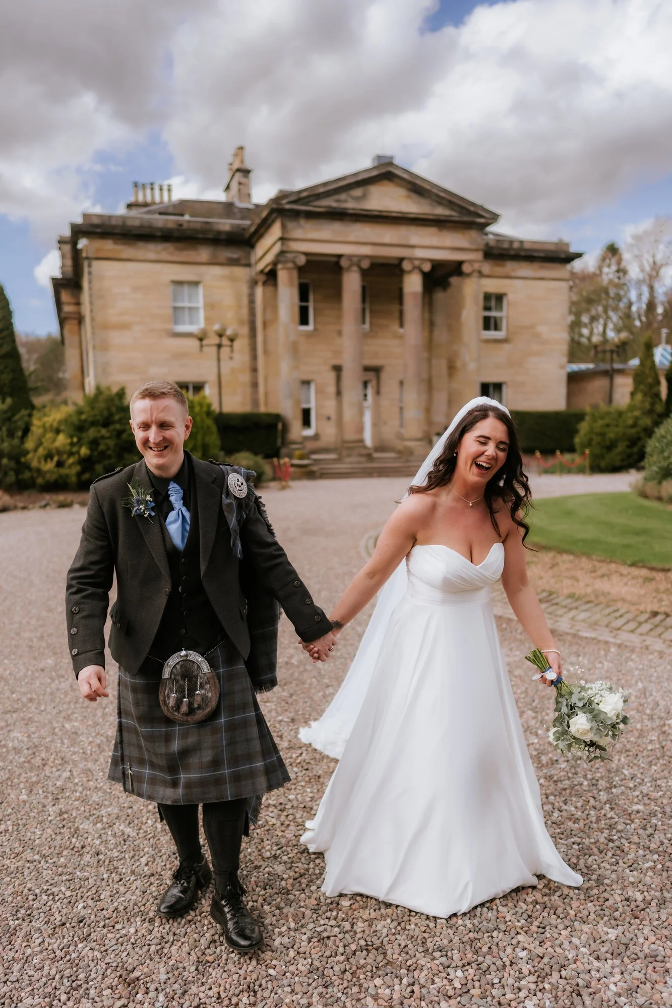 The newlyweds laughing as they walk through the grounds.