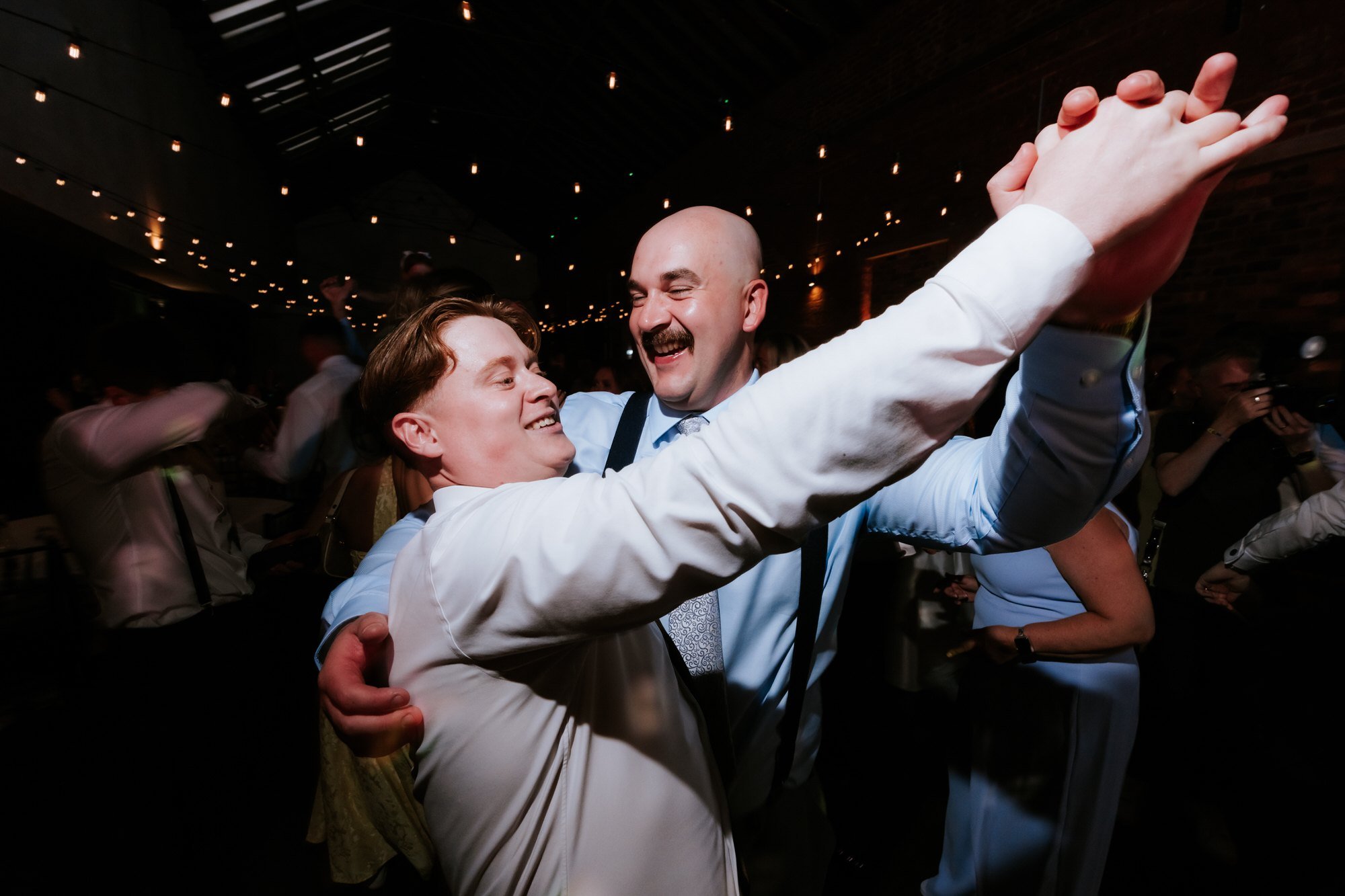 Two guests laughing and dancing together at the evening reception.