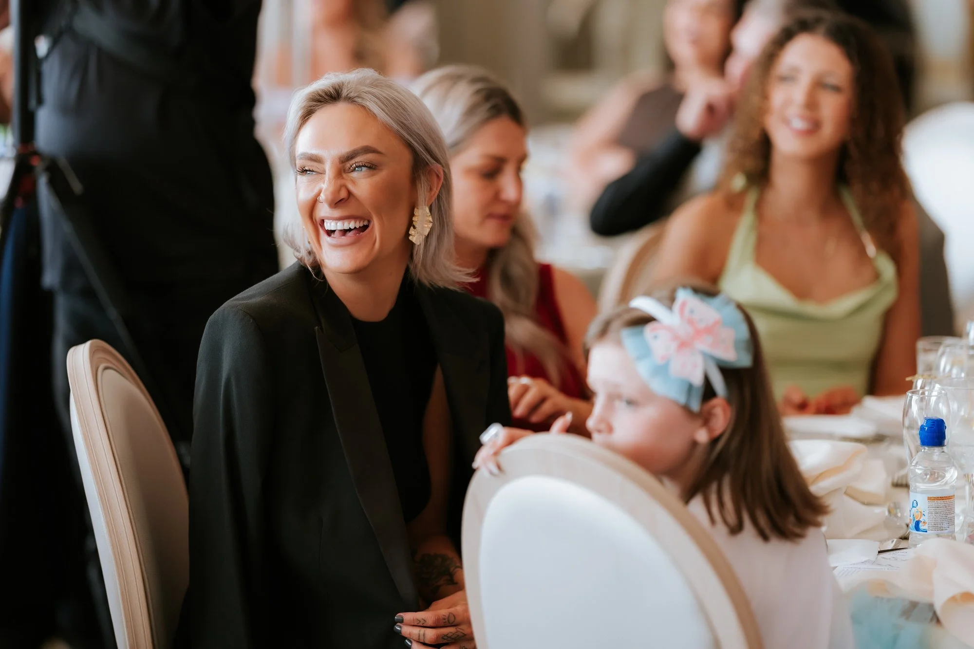 A wedding guest laughing beside a flower girl at the reception.