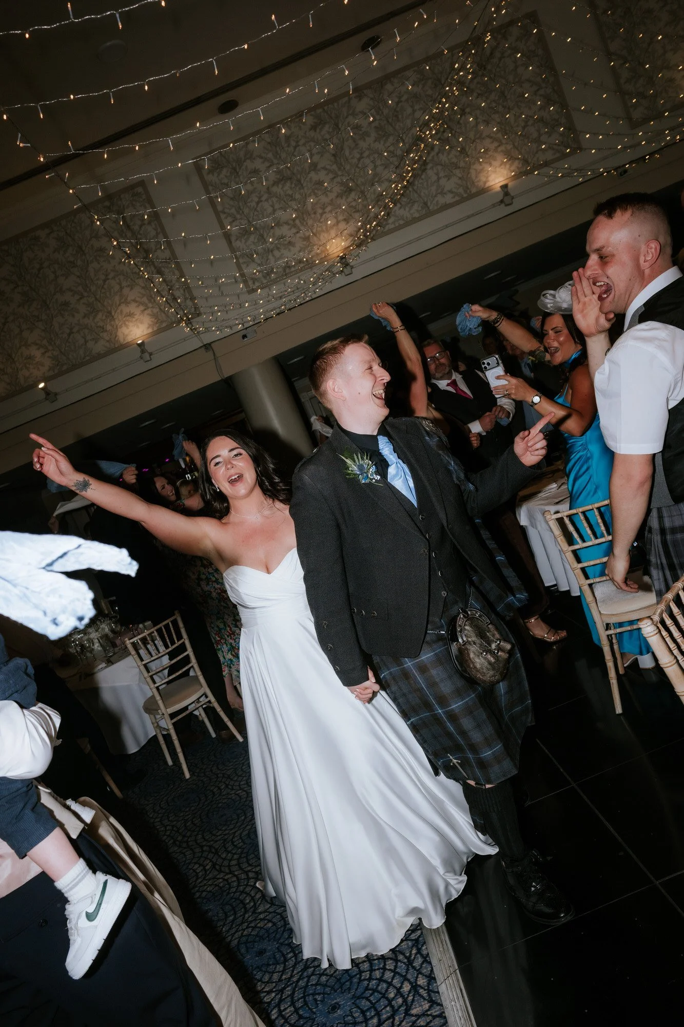 Steph and Calum entering their reception as guests wave napkins.