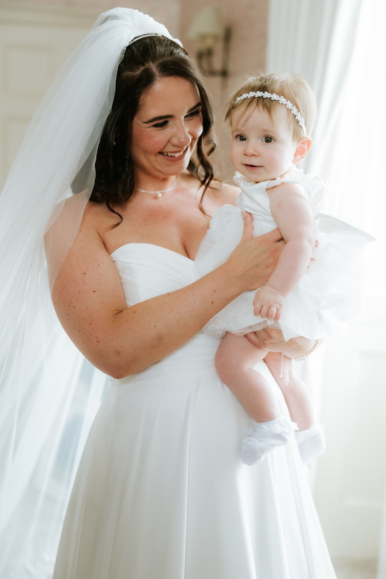 Steph holding her baby in her wedding dress.