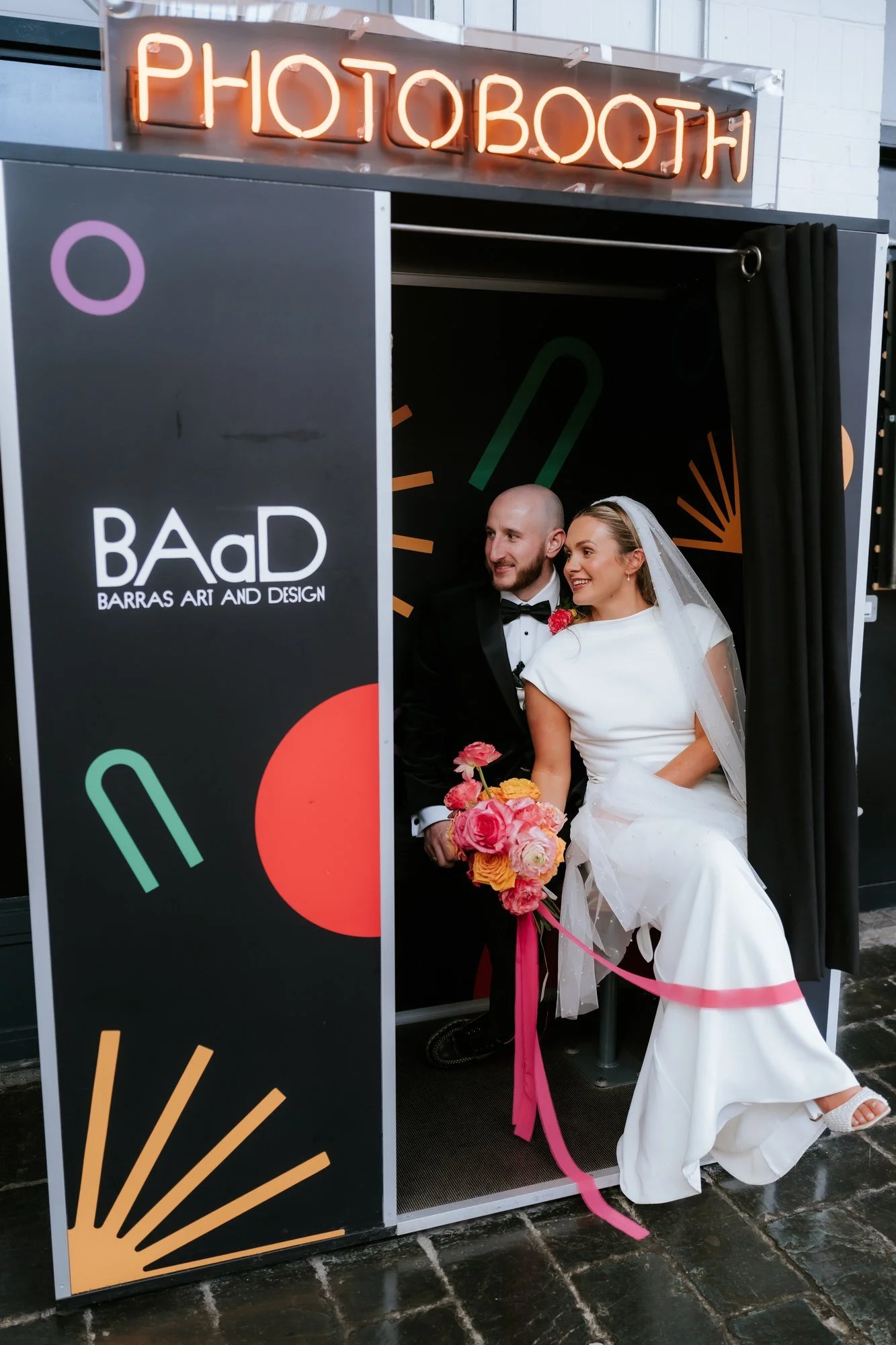 The couple together beside a photobooth at BAaD.