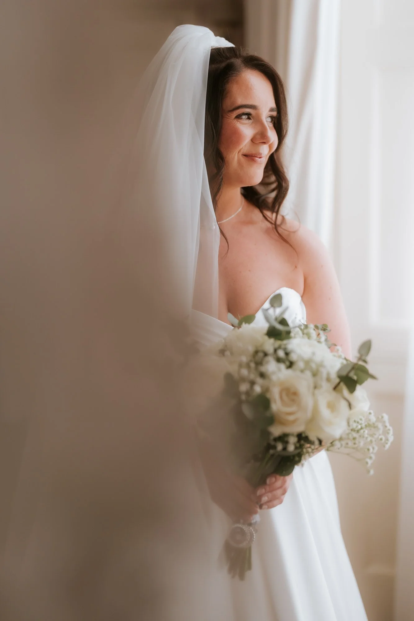 Steph in her wedding dress beside a window at Balbirnie House.