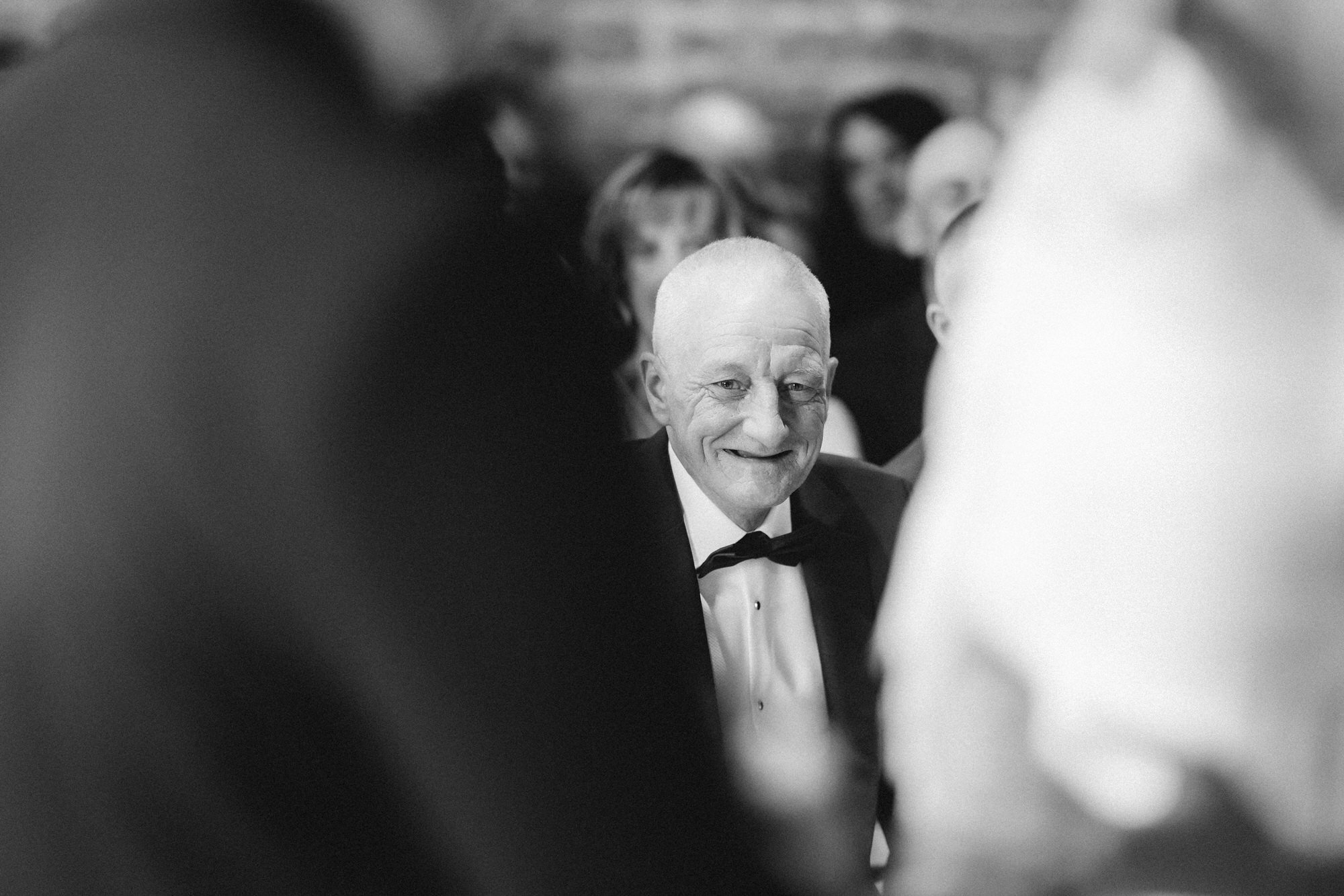 Black and white photograph of a smiling guest framed between the couple.
