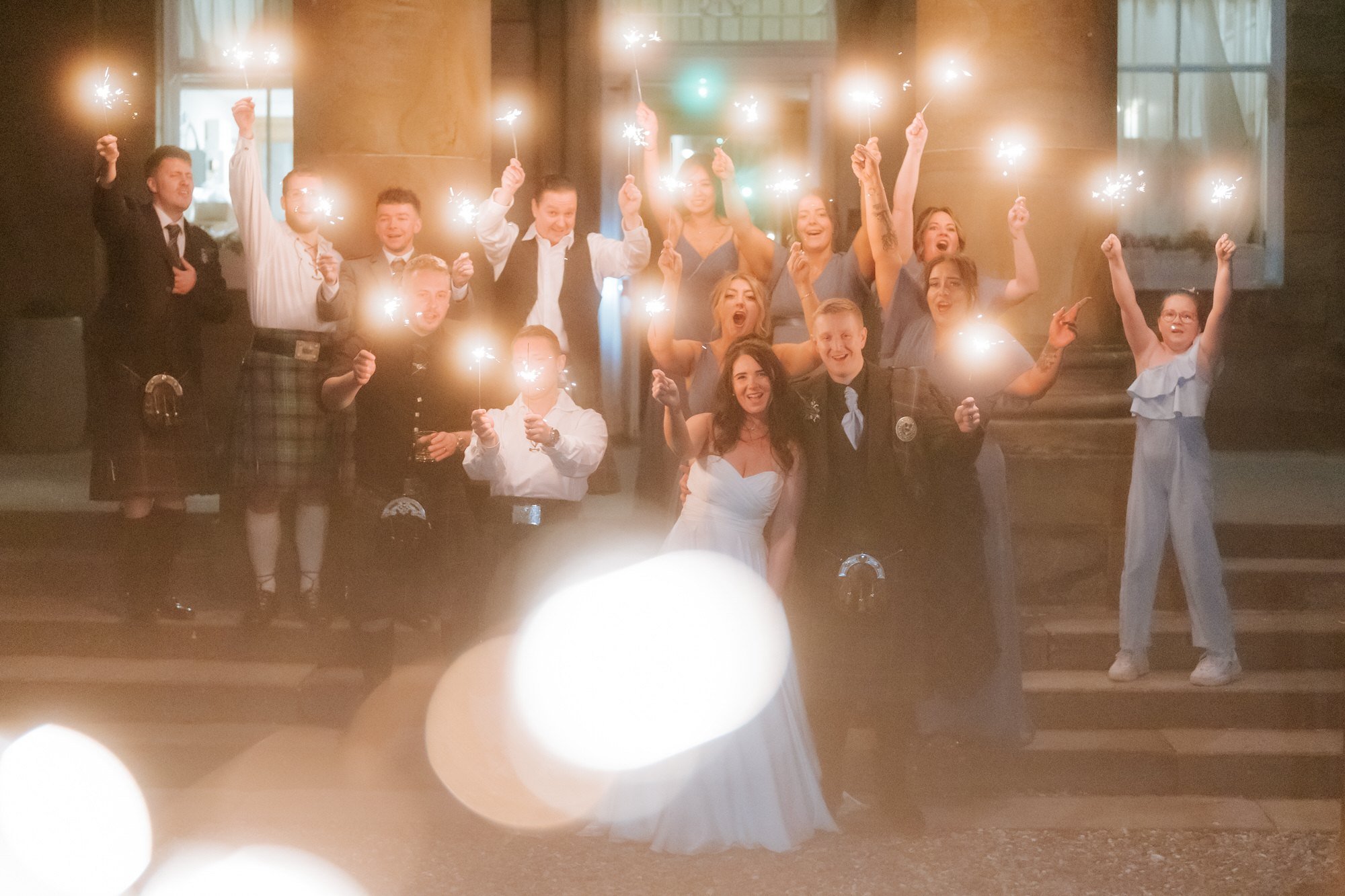 The wedding guests gathered on the steps with glowing sparklers.