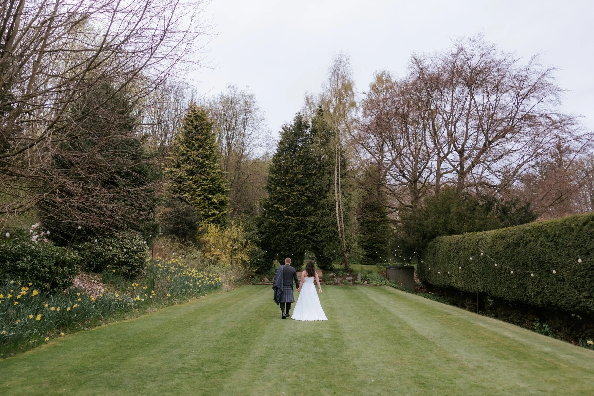 Steph and Calum walking through Balbirnie's gardens in the evening.