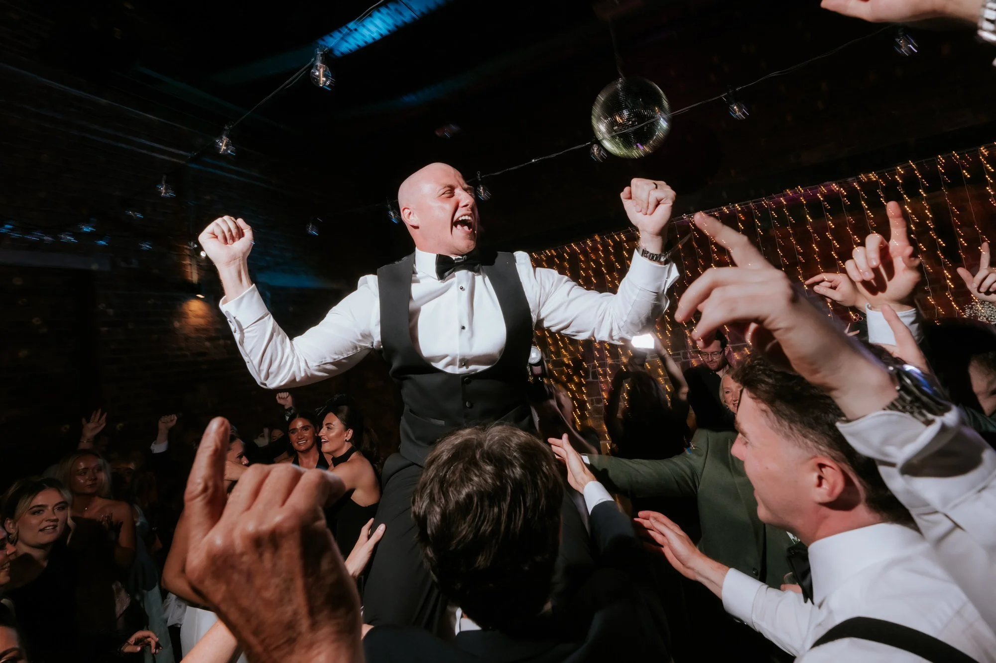 Craig lifted above the crowd with his arms raised on the dance floor.
