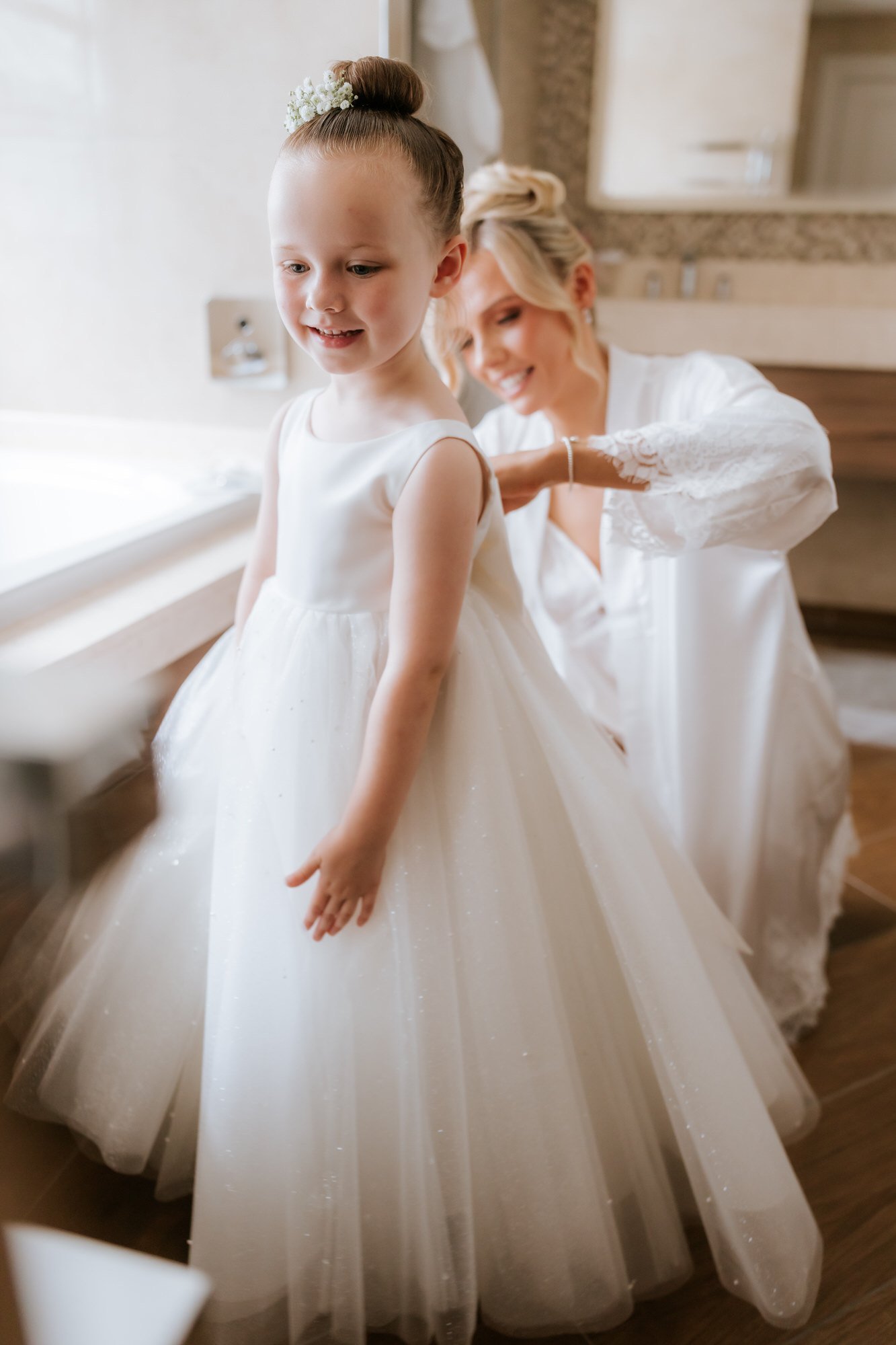 Nicole helping a flower girl beside the window on her wedding morning.