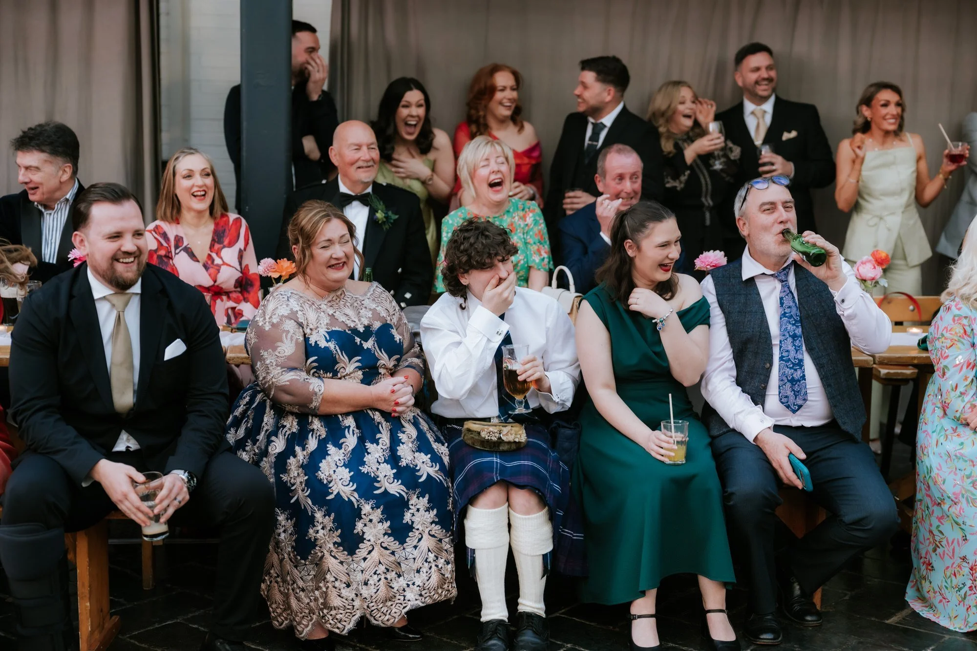 Guests laughing together around a reception table.