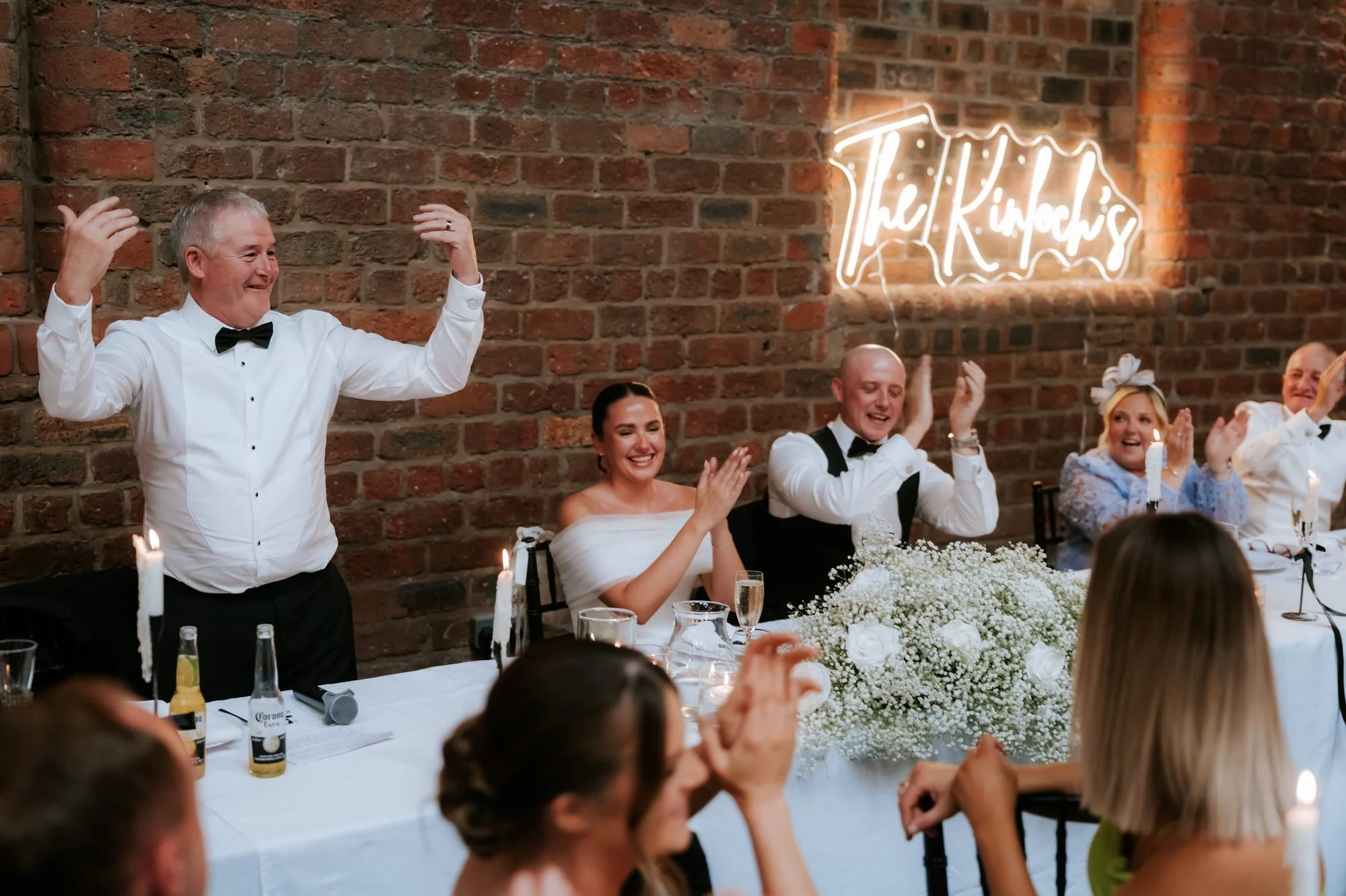 Caitlin and Craig applauding at their candlelit wedding reception.