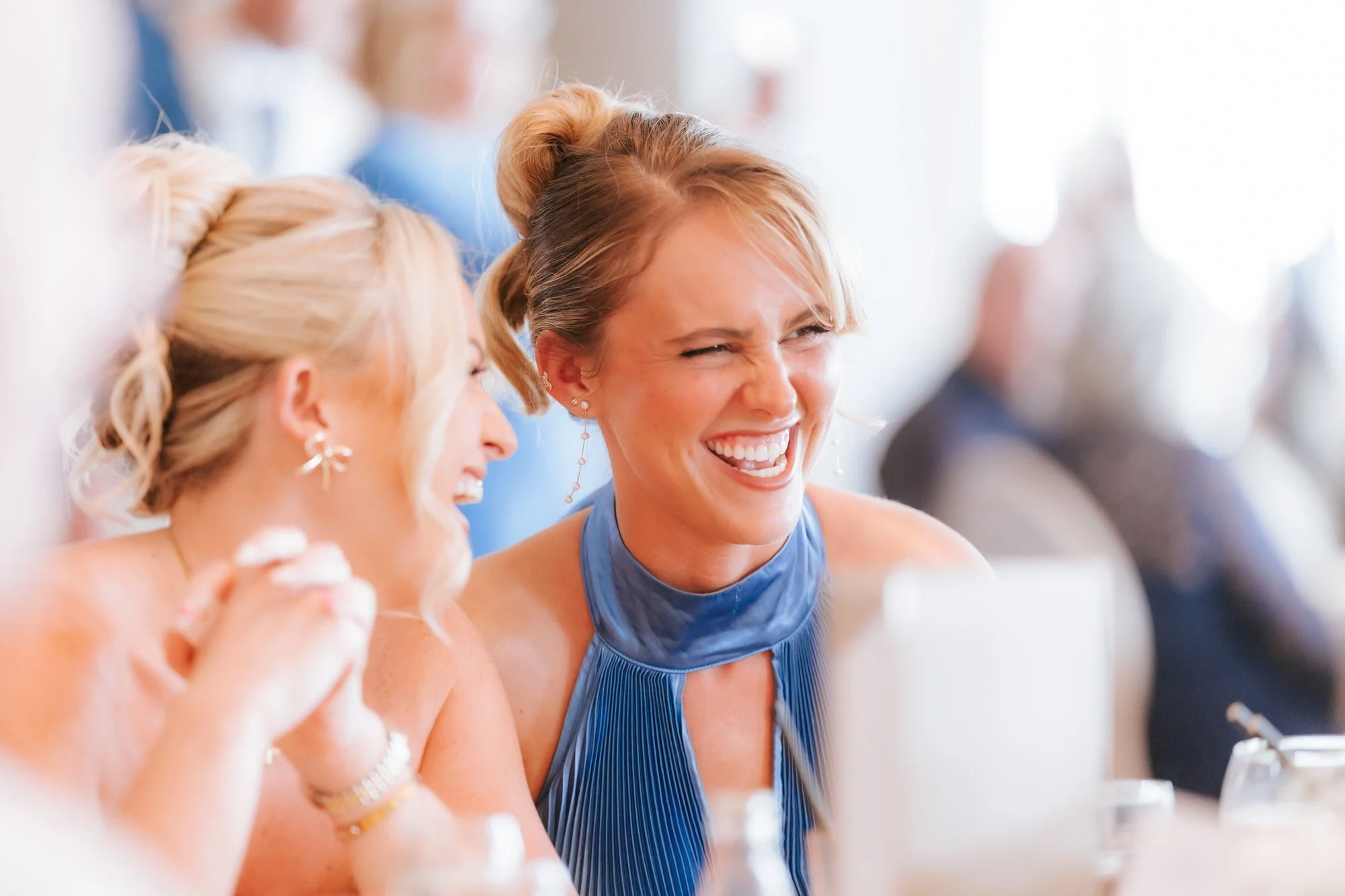 Two guests laughing together during the wedding speeches.