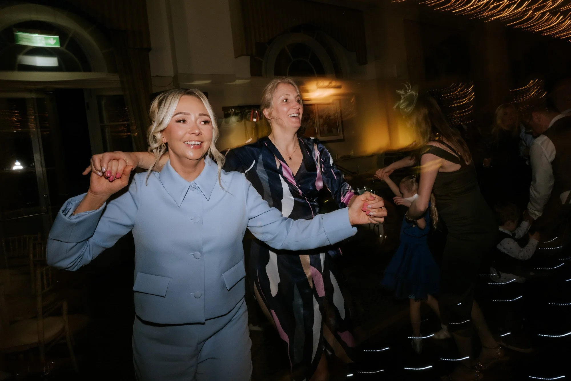 Wedding guests dancing and laughing together.