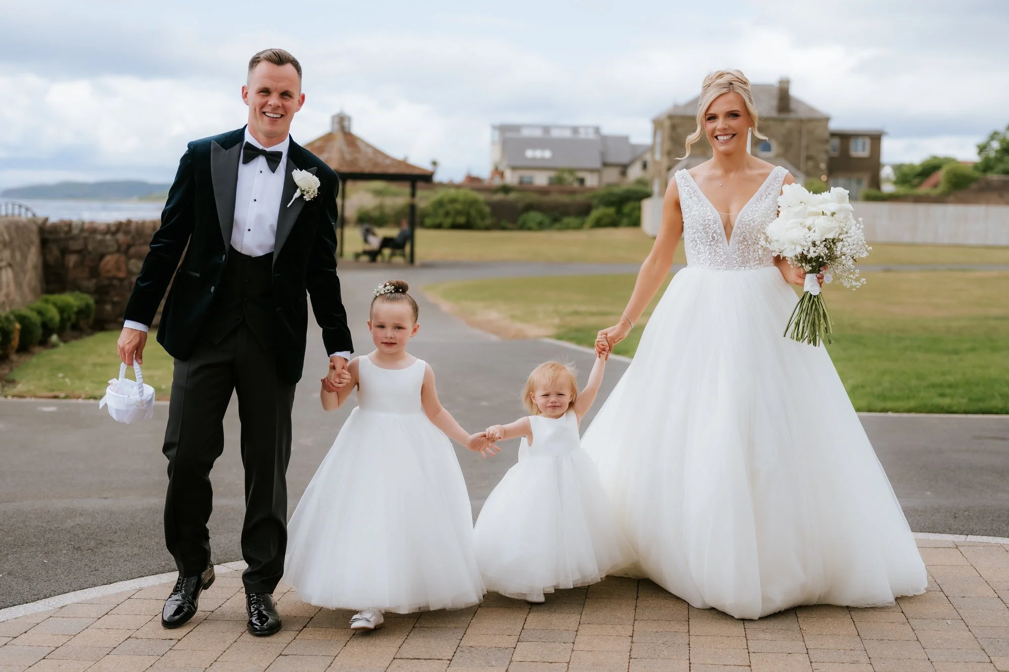 Nicole and Lawrence holding hands with their two daughters during family photographs.