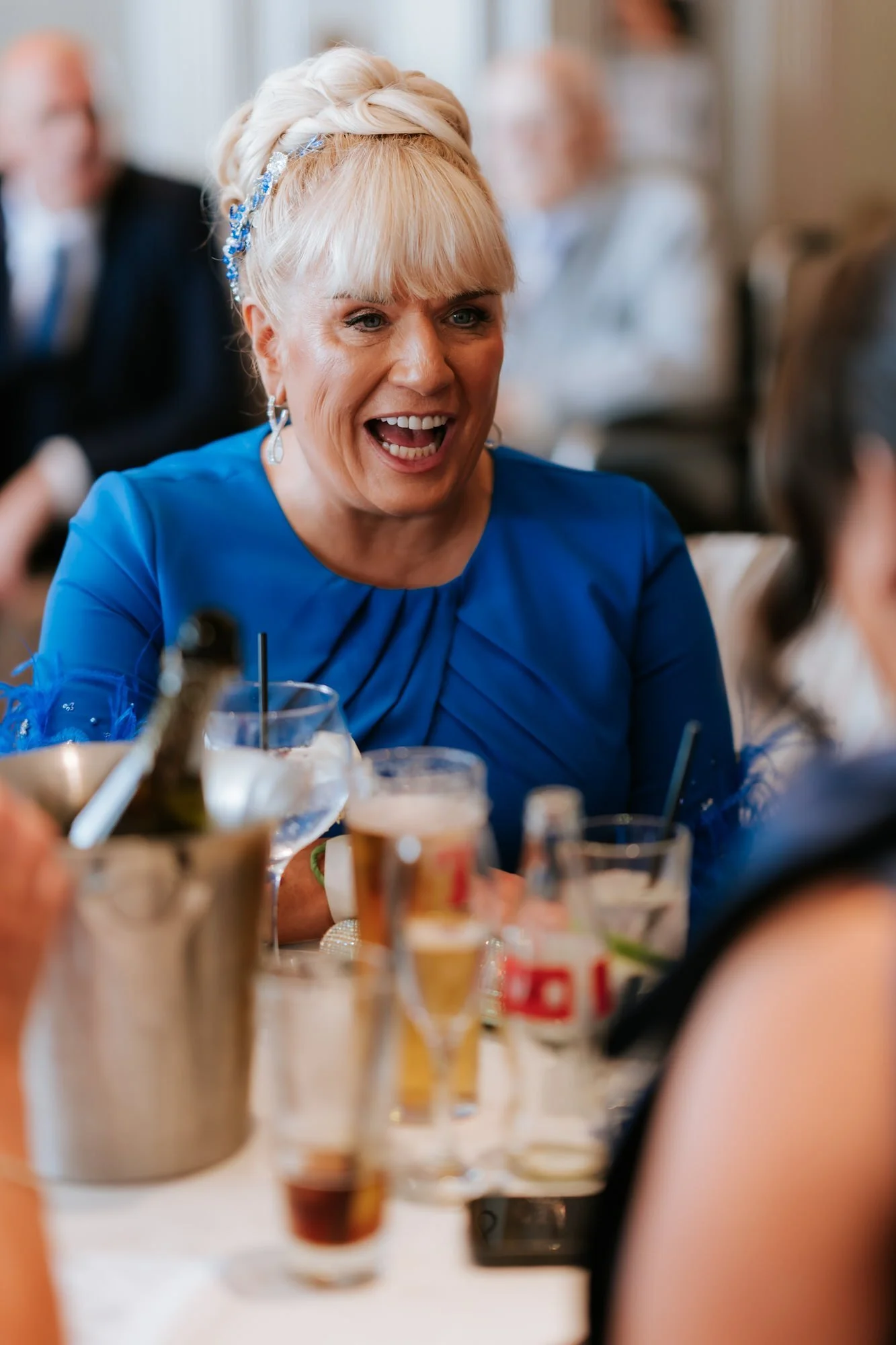 A guest in blue laughing at the wedding reception.