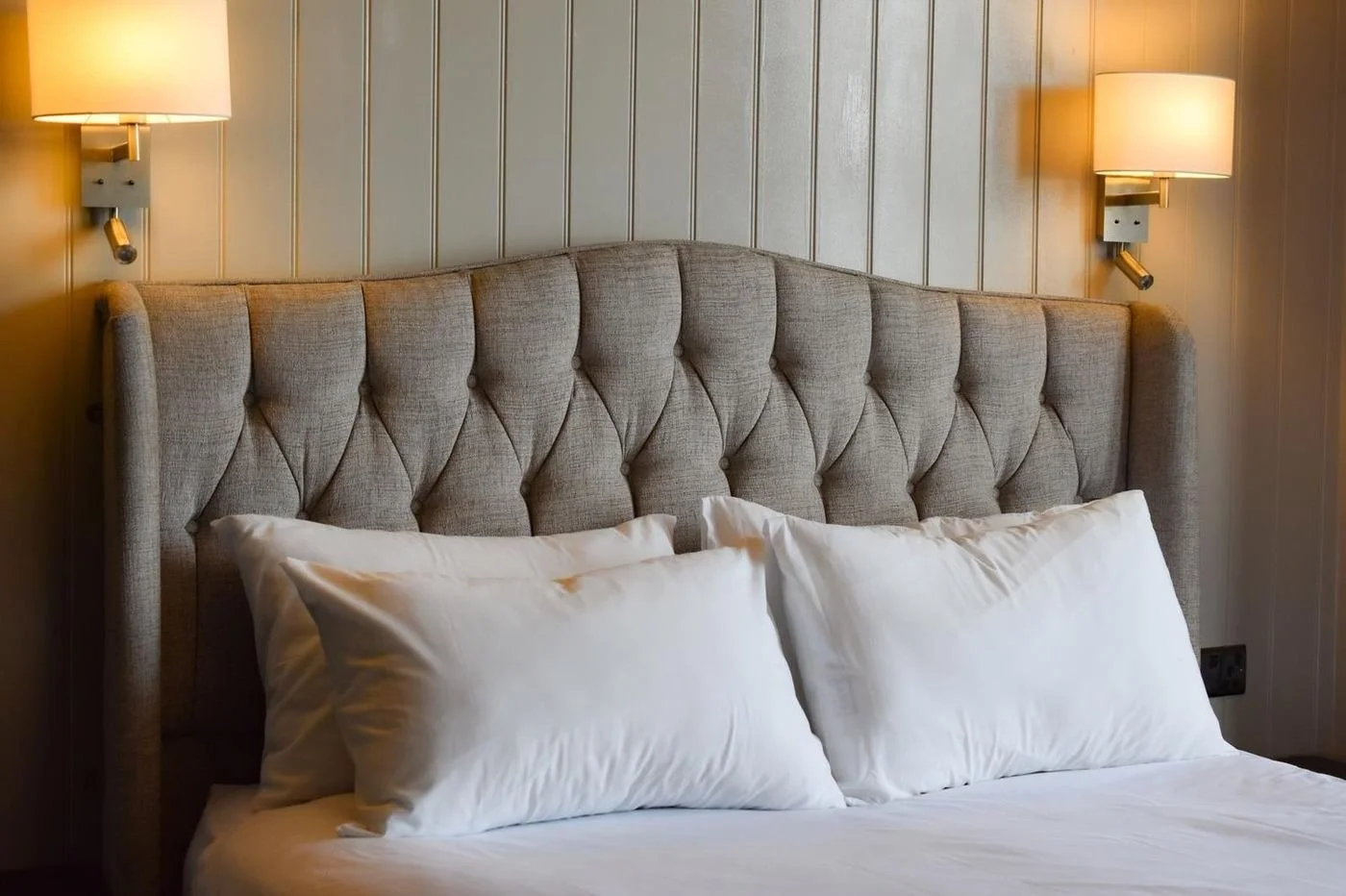 A sea-view room with a tufted headboard and wall lamps