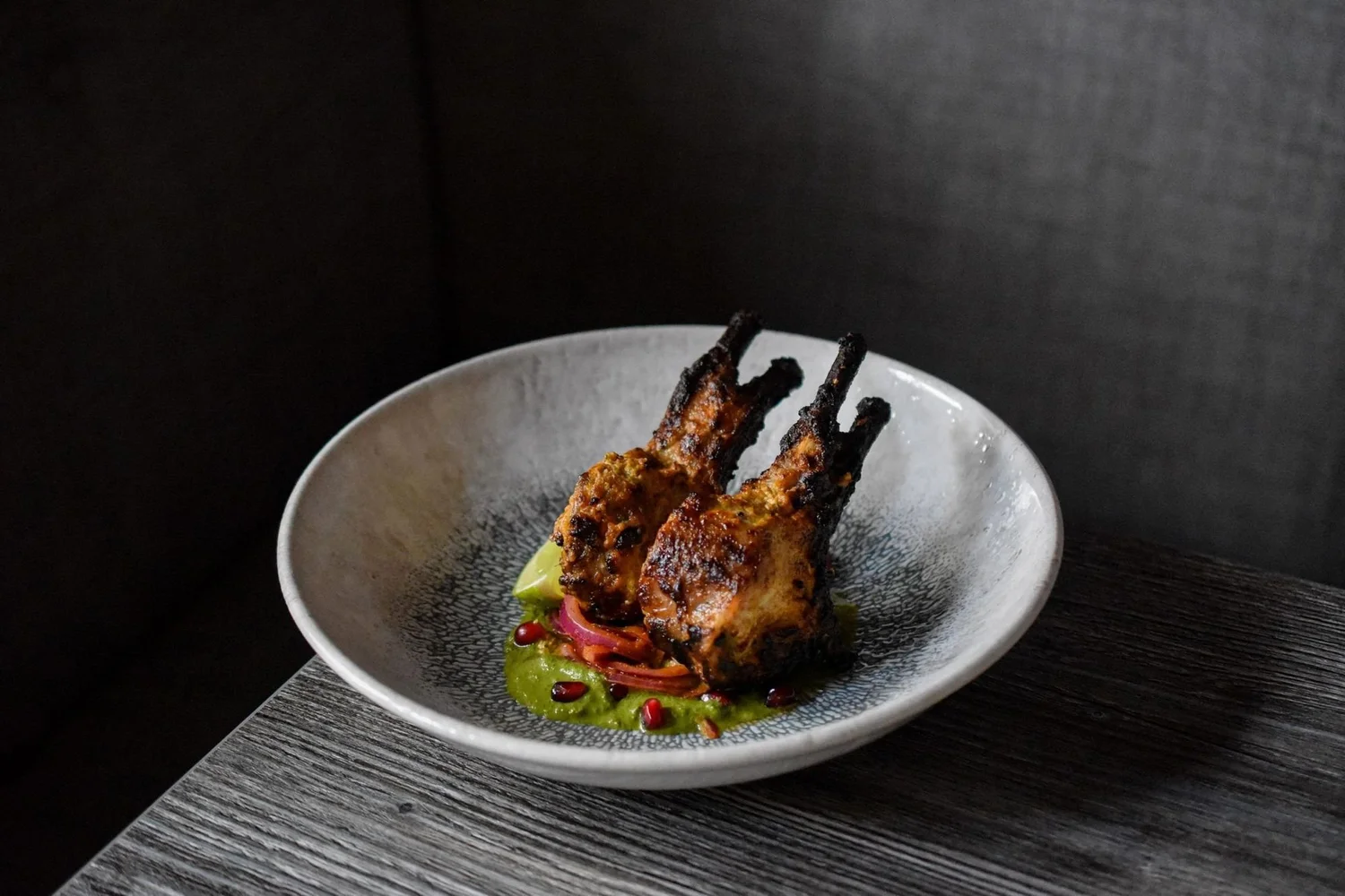 Lamb chops in a speckled bowl on a dark table