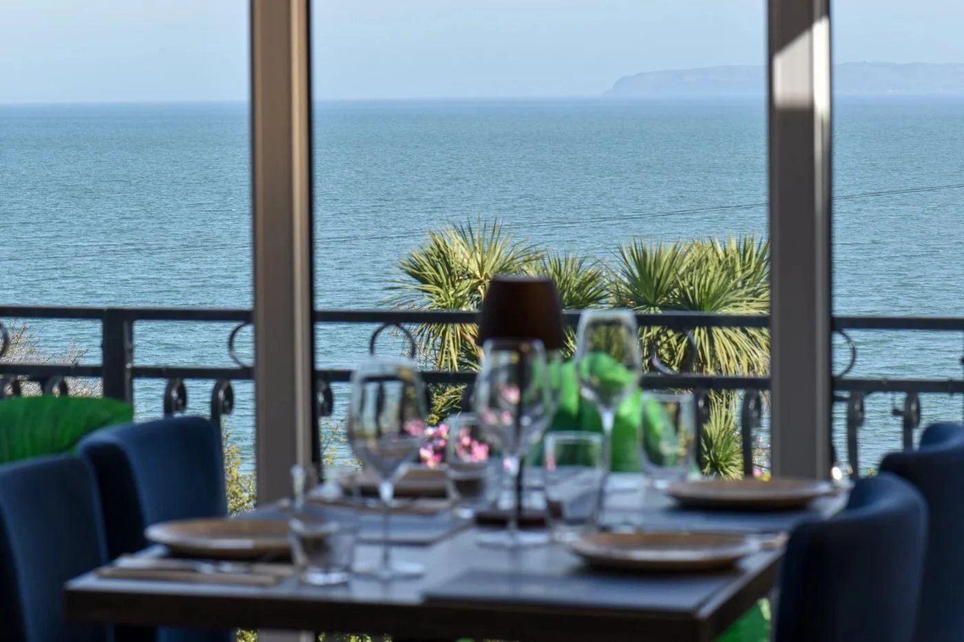 A laid table by the window with the sea beyond