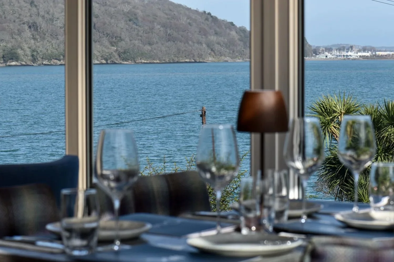 A laid table in the dining room, with the sea and the hills beyond the windows
