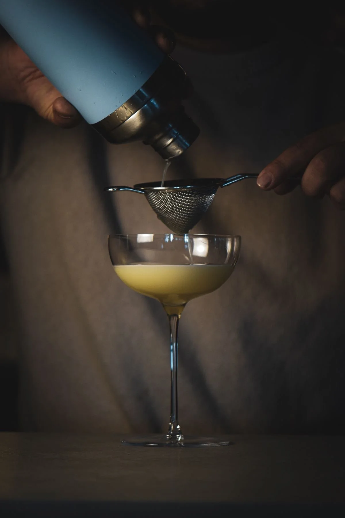A cocktail strained into a coupe at the bar