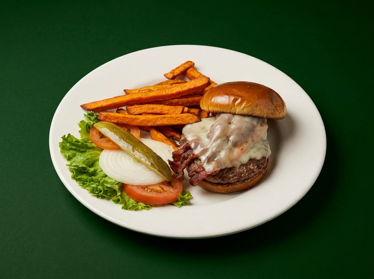 A burger with sweet potato fries, lettuce, tomato and pickle