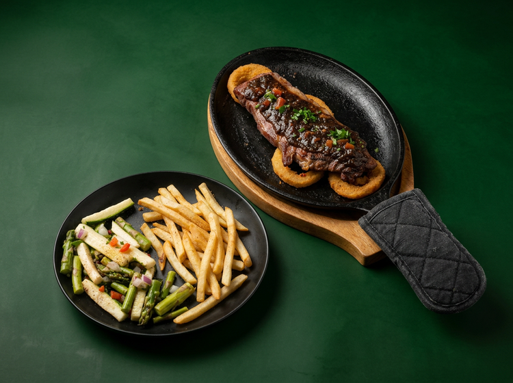 New York strip steak on a sizzling skillet, with fries and vegetables on the side