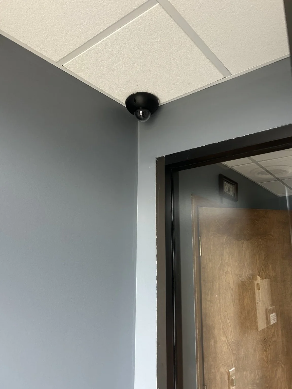 Black dome security camera neatly installed in the corner above an interior doorway