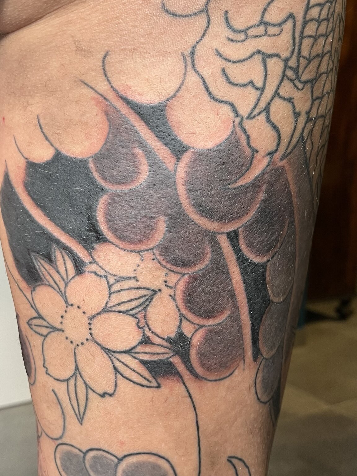 Detail of a black-and-grey Japanese flower and wave tattoo.