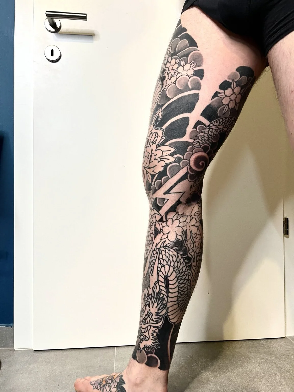 Black-and-grey Japanese dragon and flower leg sleeve.