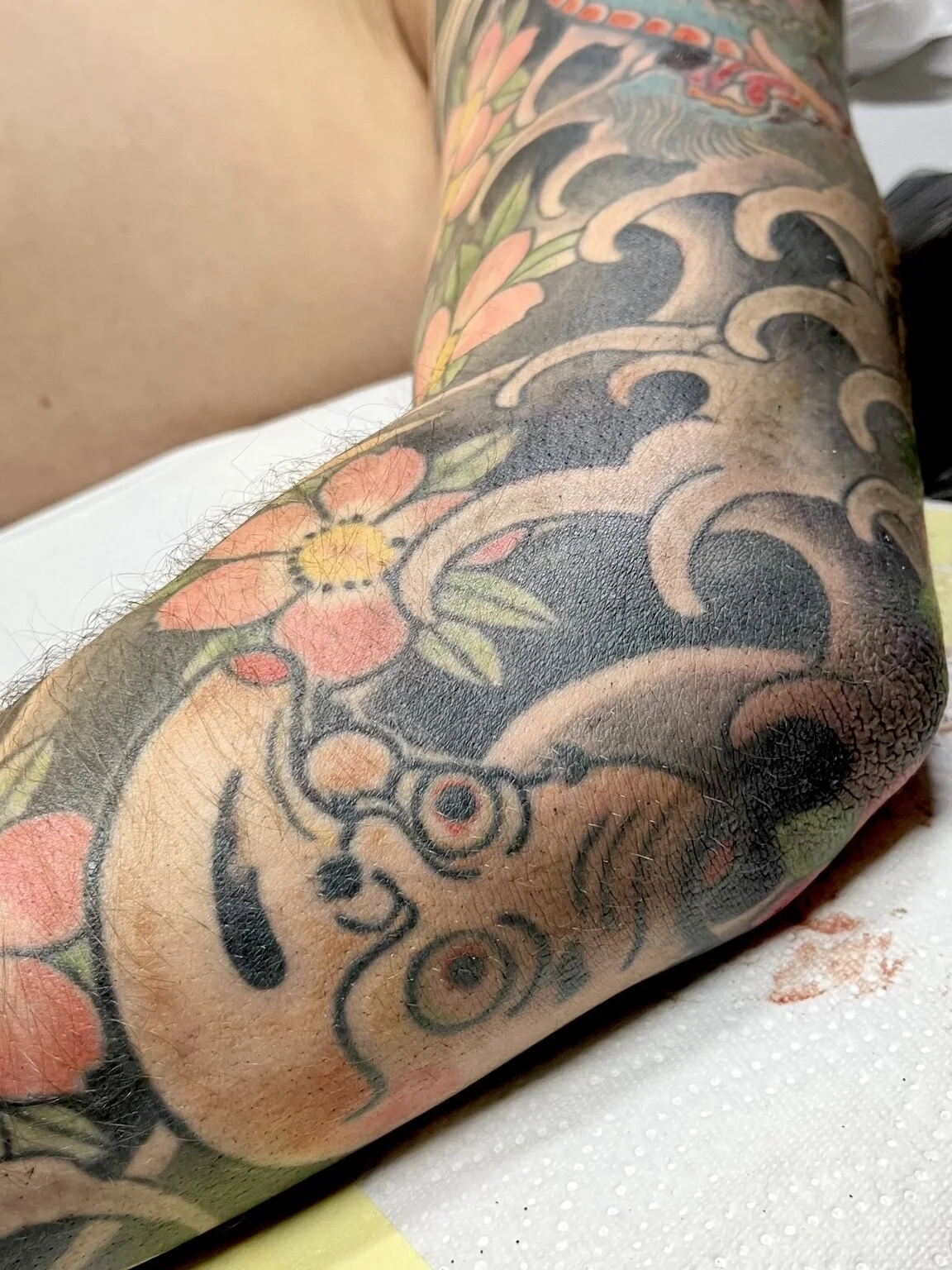 Detail of a Japanese frog tattoo with cherry blossoms and waves.