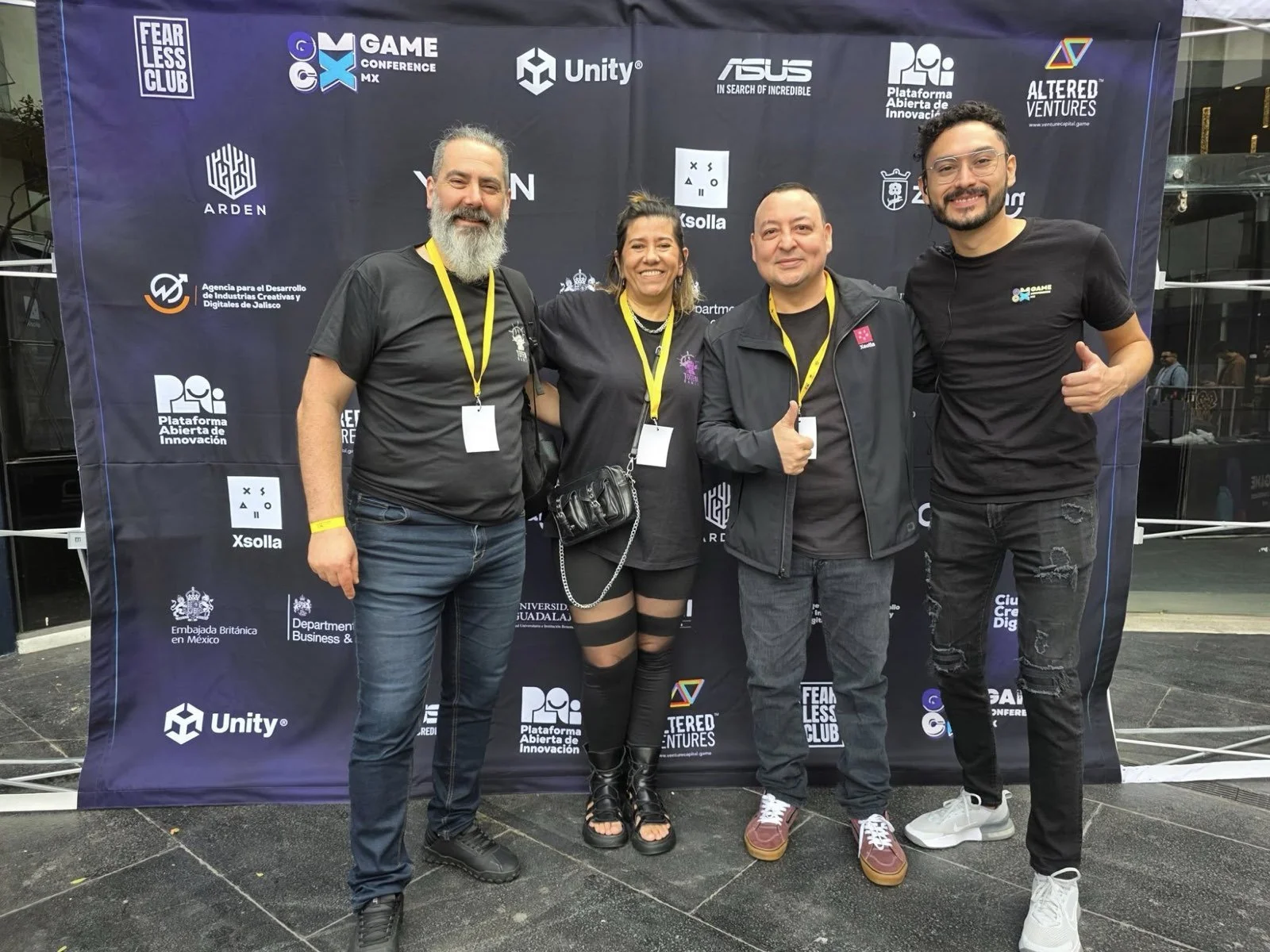 El fundador y un equipo participante frente al muro de patrocinadores de GCMX 2025