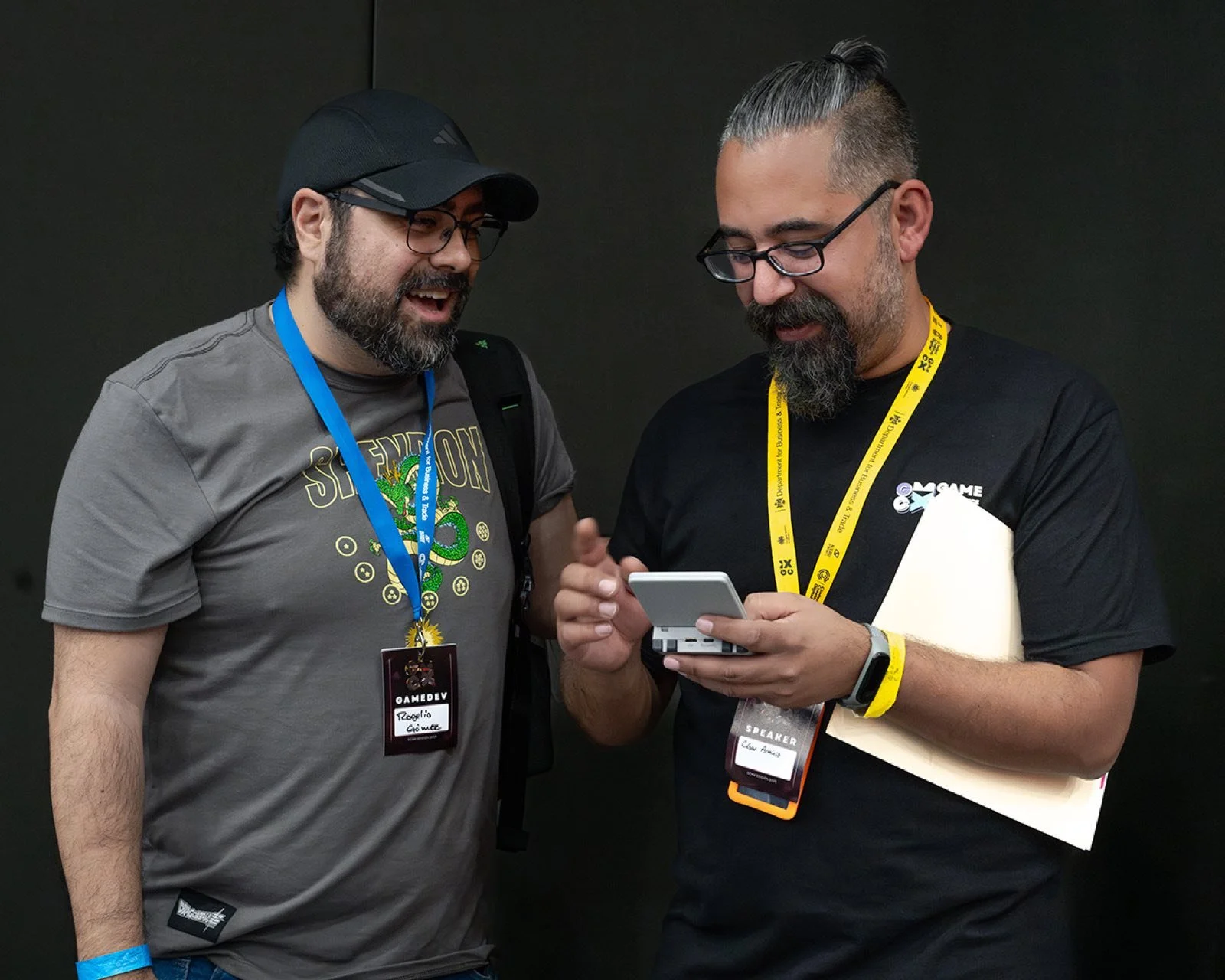 Dos asistentes de GCMX 2025 compartiendo un juego en consola portátil
