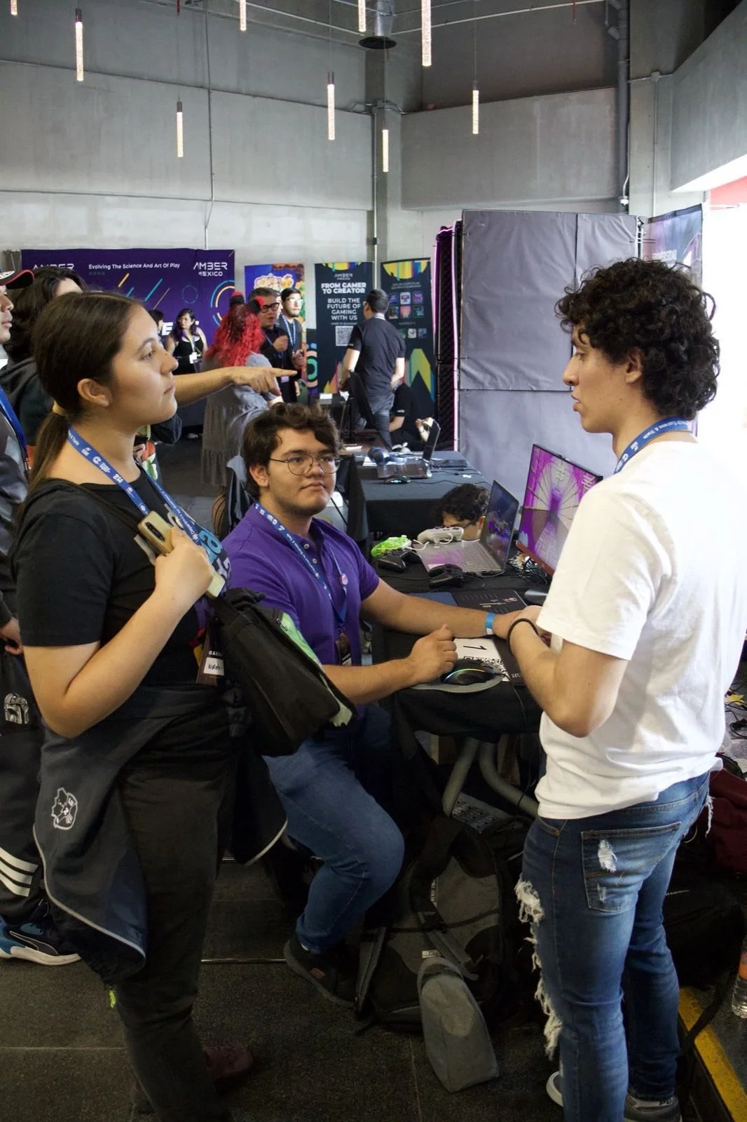 Staff de un stand conversando con asistentes en GCMX 2025