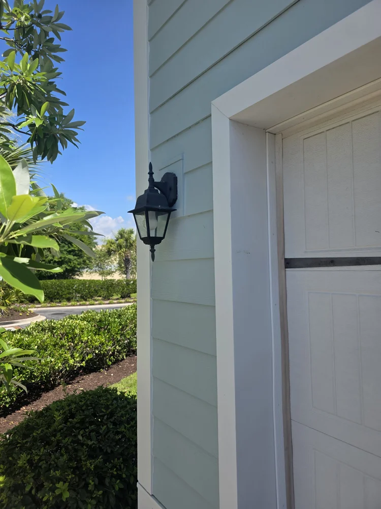 Black exterior wall lantern beside a garage