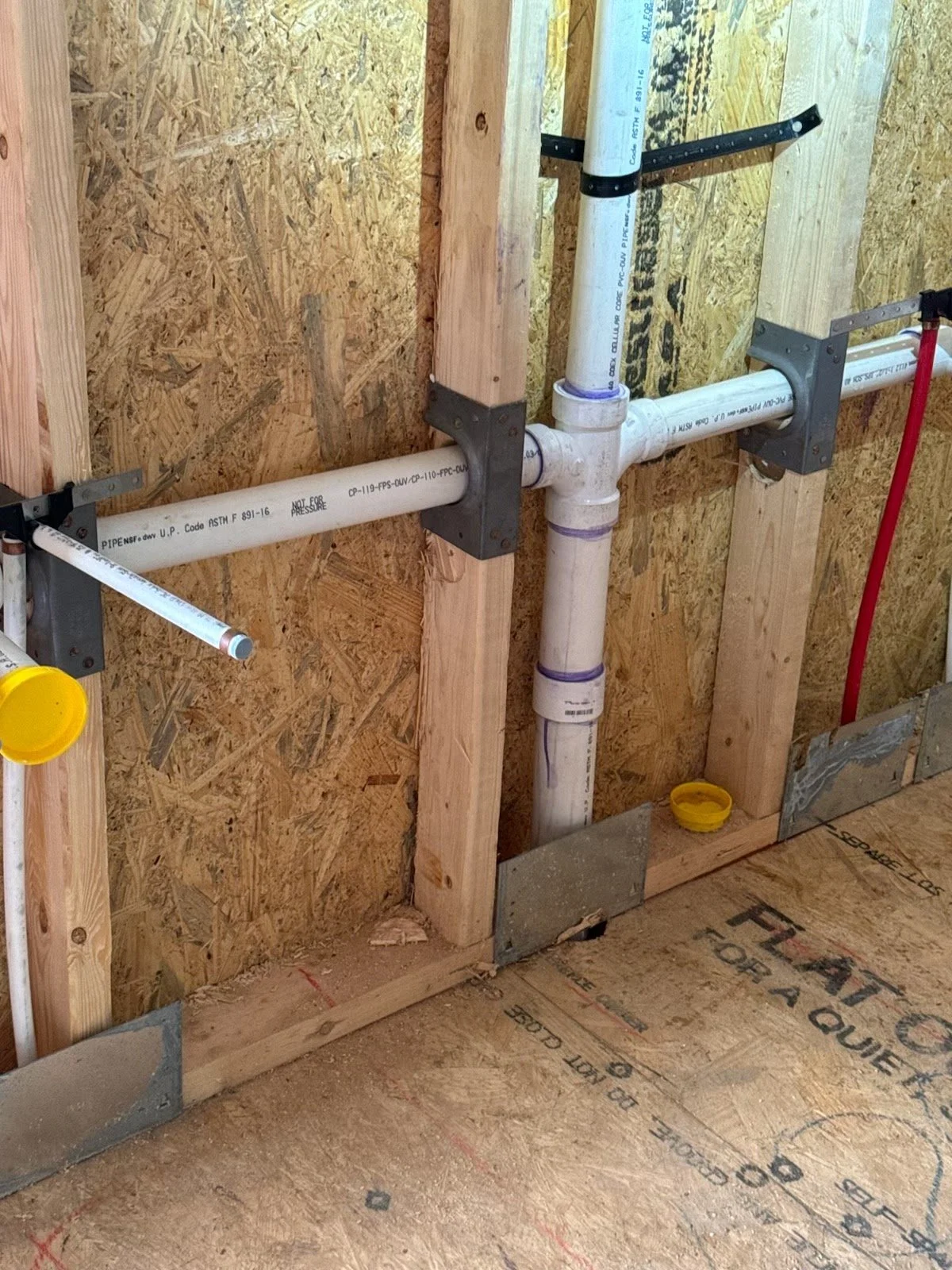 PVC drain and vent piping with nail plates through studs