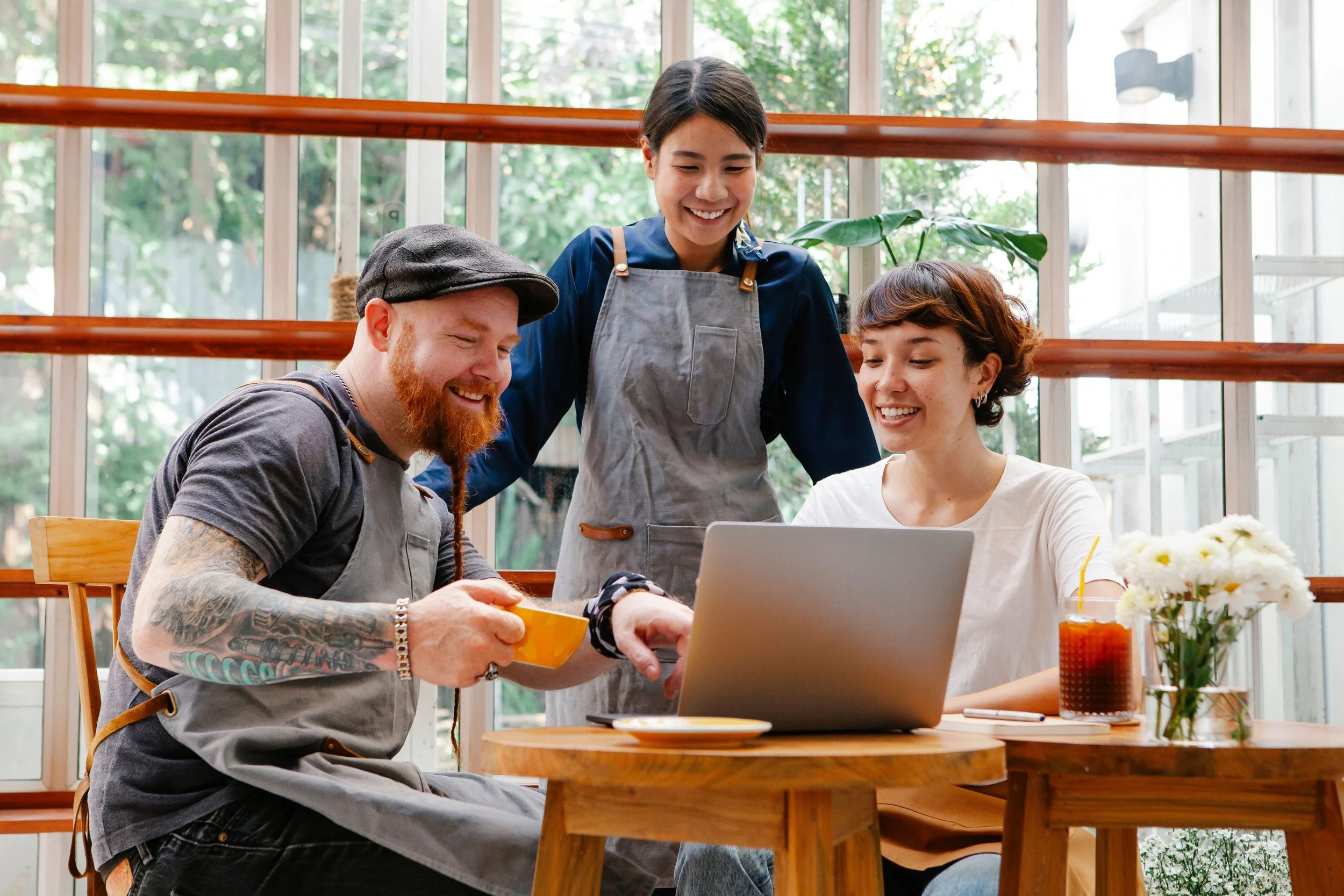 Café colleagues discussing work together around a laptop