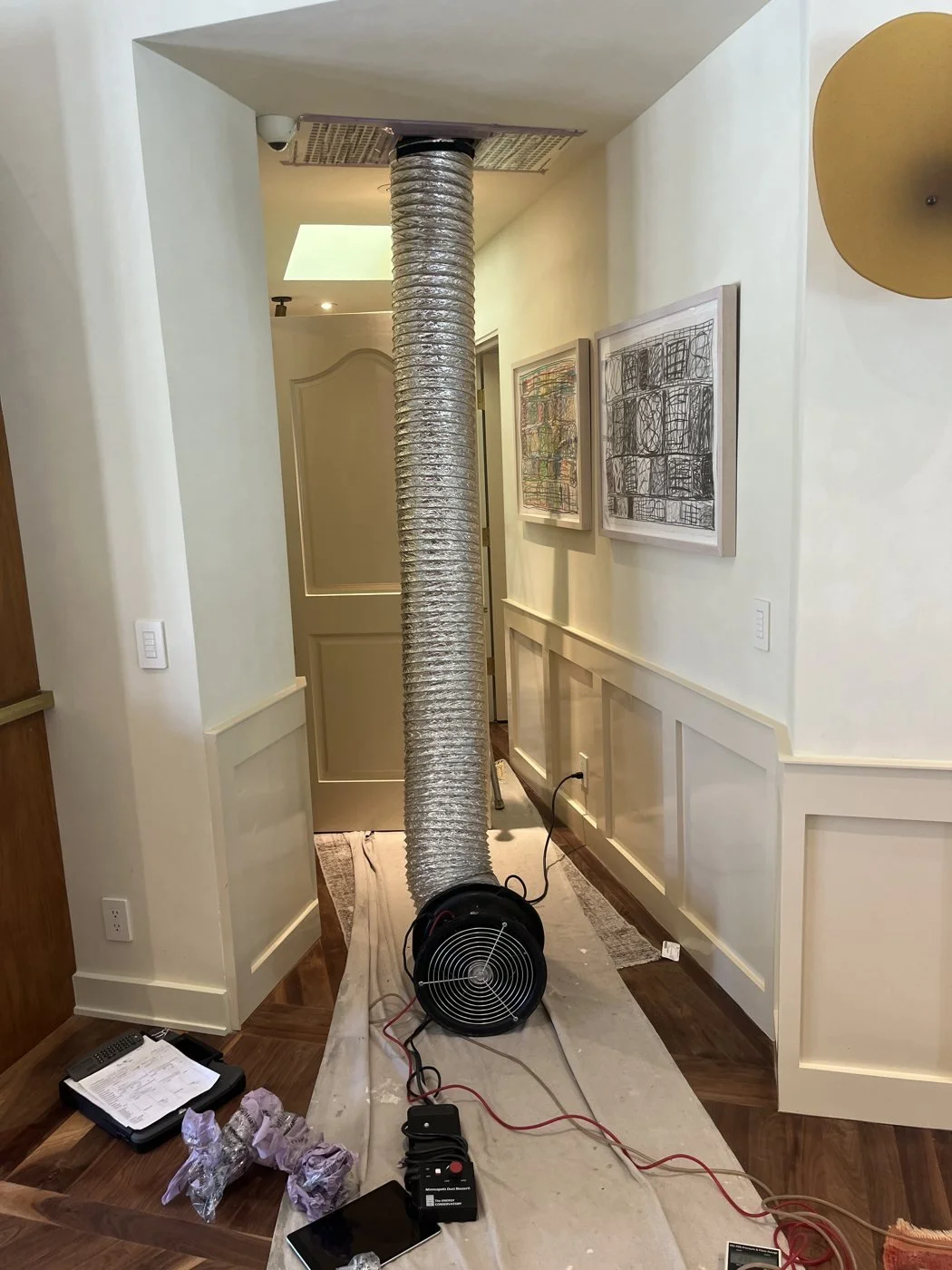 Duct leakage test fan connected at a return grille in a finished home