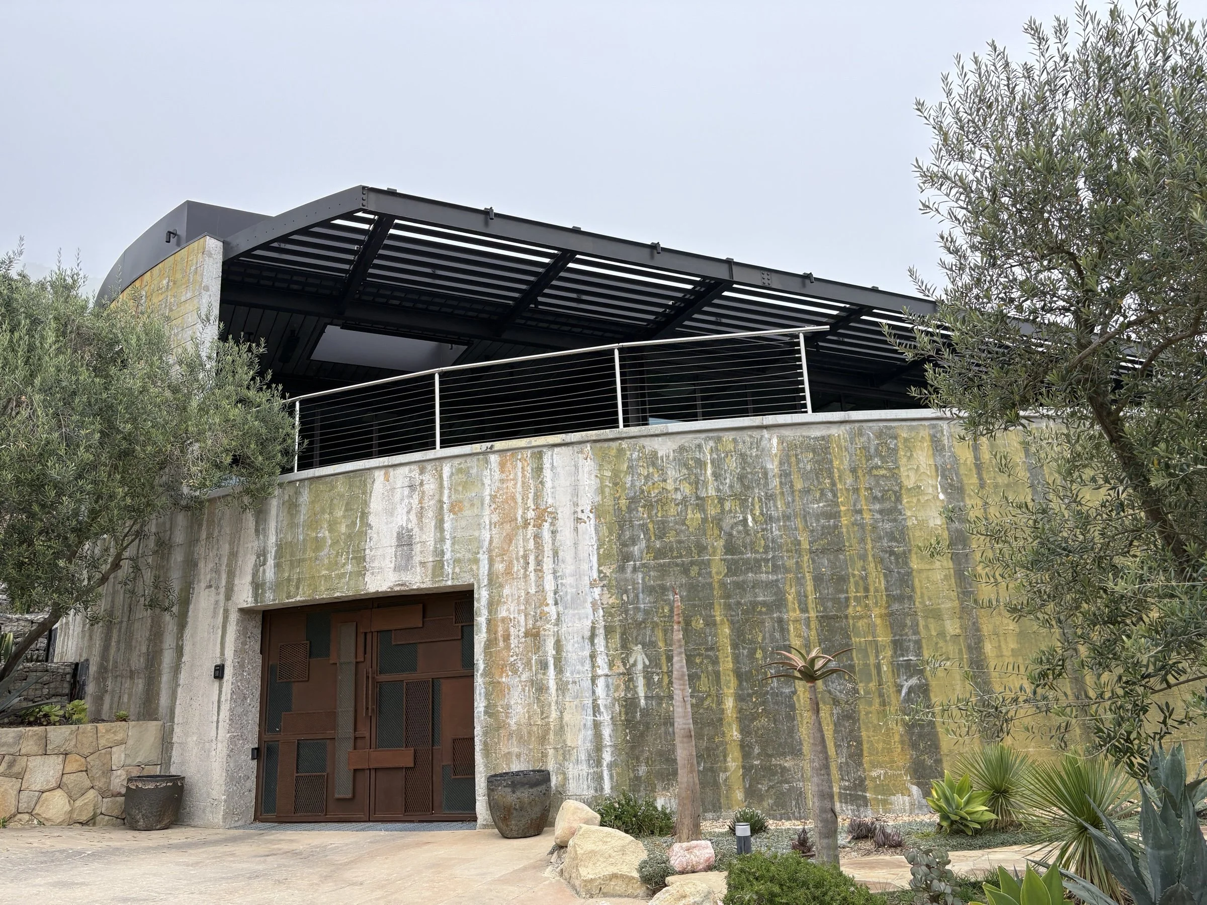 A finished modern home with a distinctive weathered concrete facade and Cor-Ten steel entry, verified for Title 24 compliance