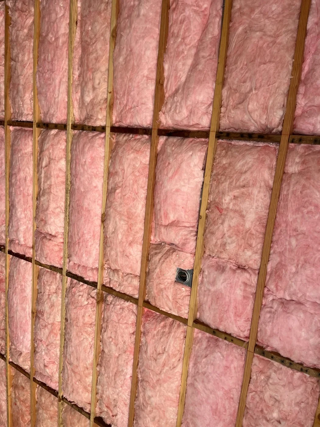Wall cavities fully filled with batt insulation, cut to fit