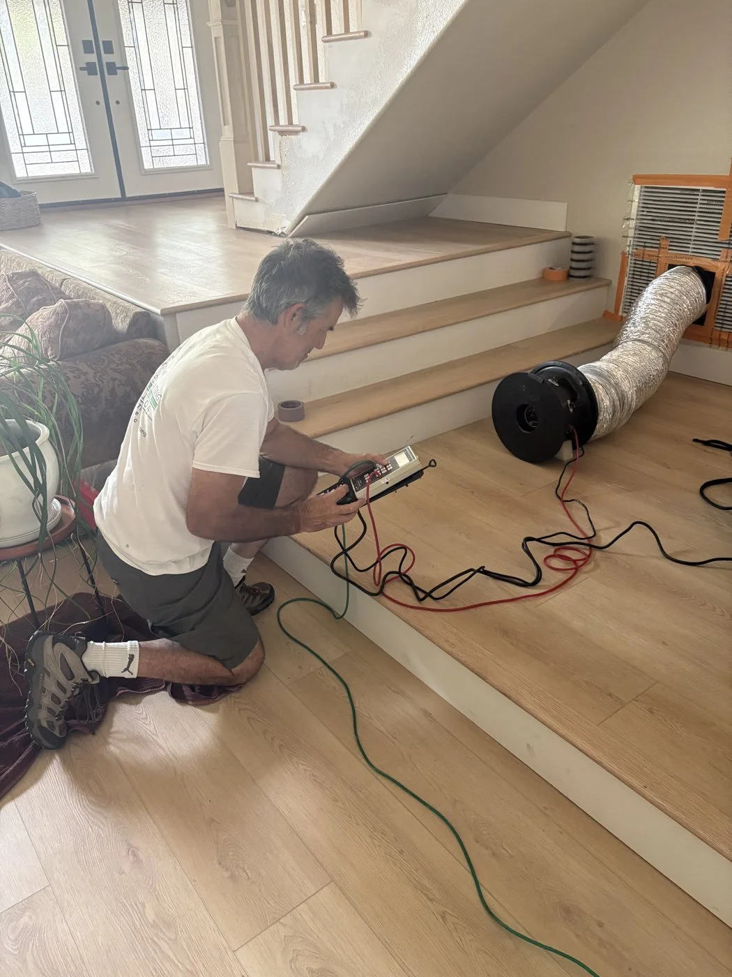Rater running a duct leakage test with a Duct Blaster and pressure gauge