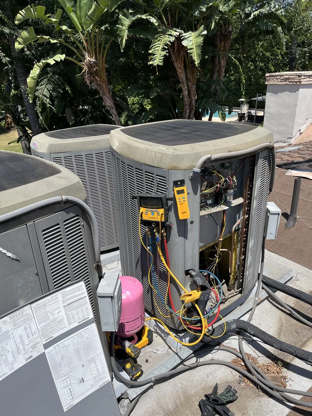 Rooftop condensers with a digital manifold and refrigerant cylinder on a scale for a weigh-in
