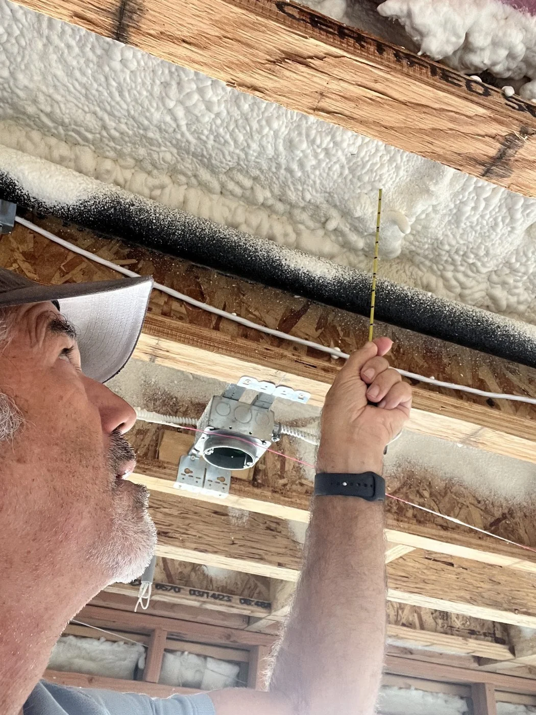 Rater measuring spray foam depth at the roof deck with a probe ruler