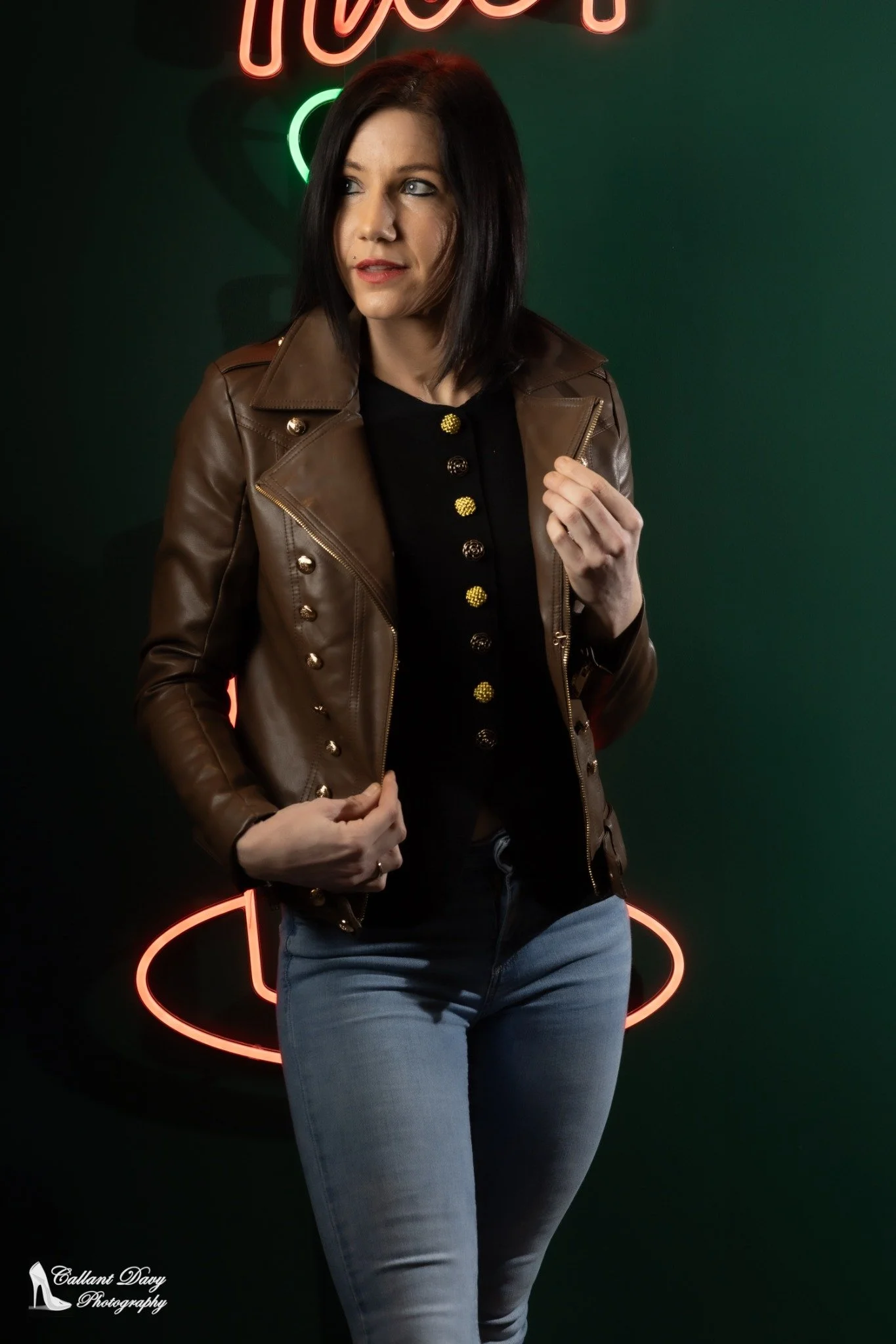 Fashionportret met bruin leren jasje en jeans bij neonlicht