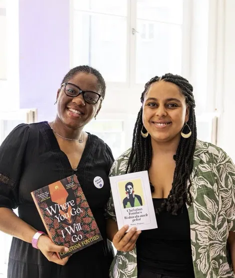 Two women holding the English and German editions of the novel