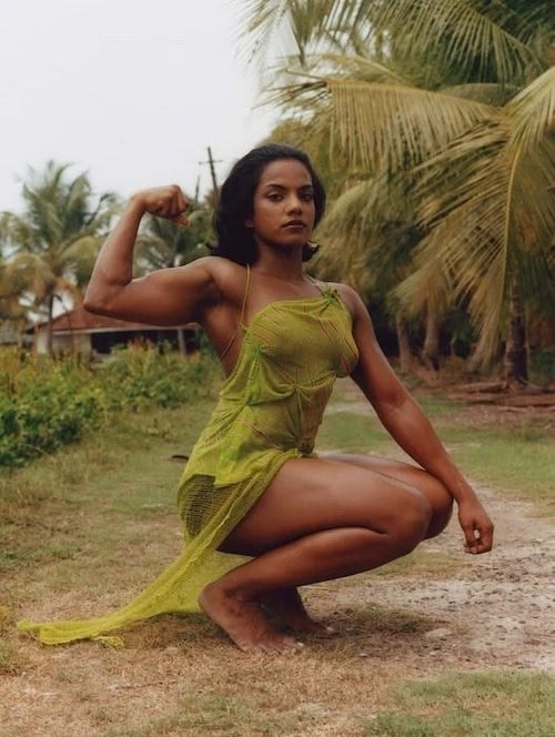 Woman in a chartreuse dress flexing among palm trees